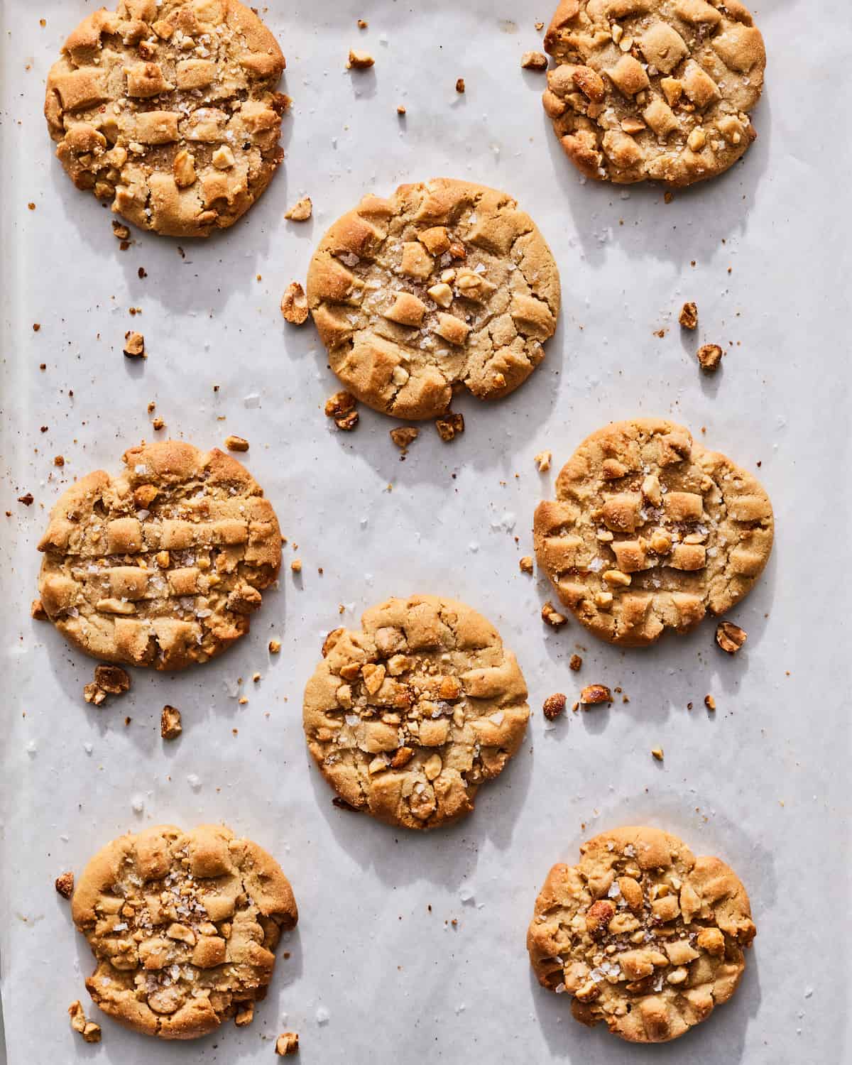 Eight Peanut Butter Cookies spread out across a piece of parchment paper.  