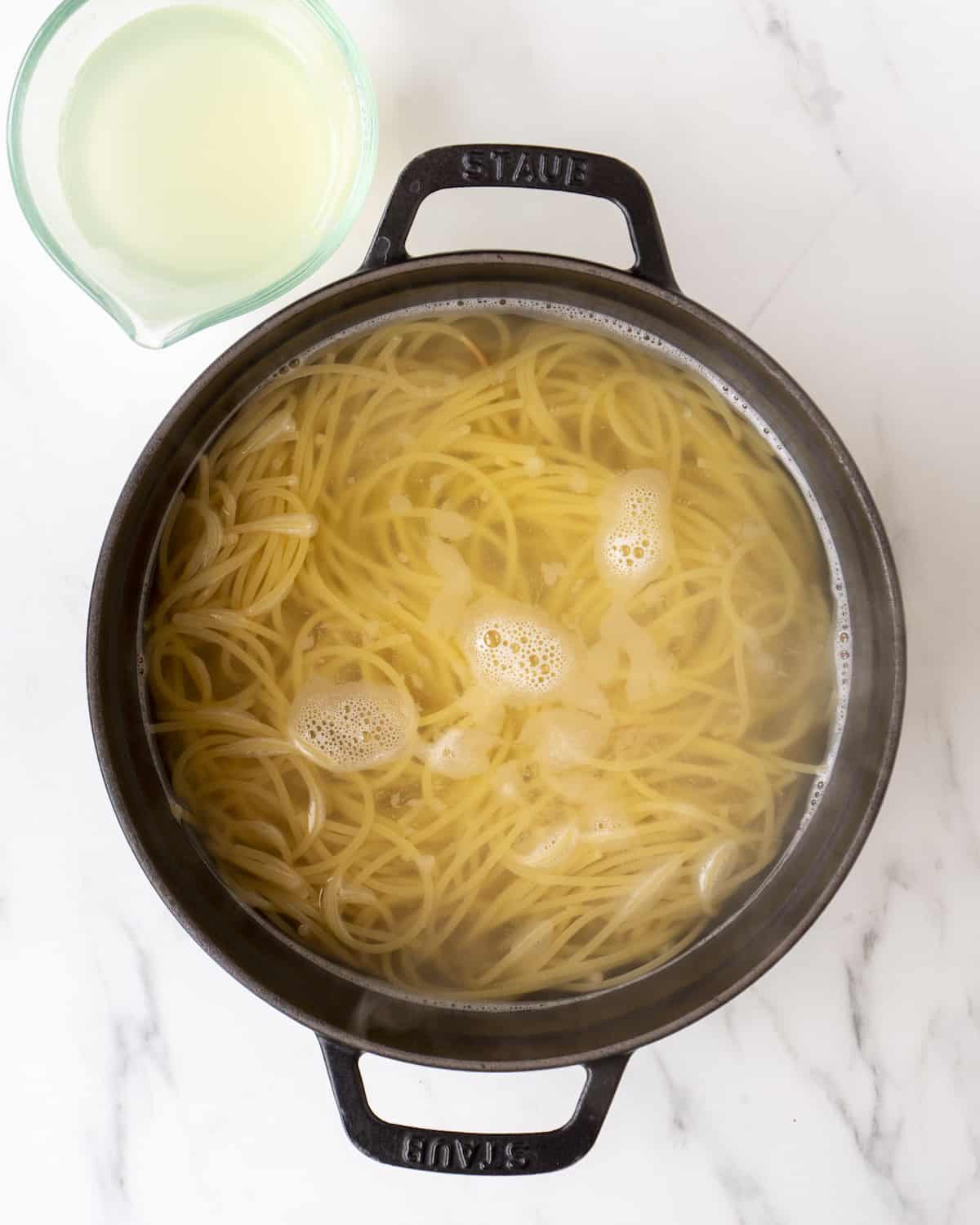 A bowl of spaghetti in a large pot of water.  