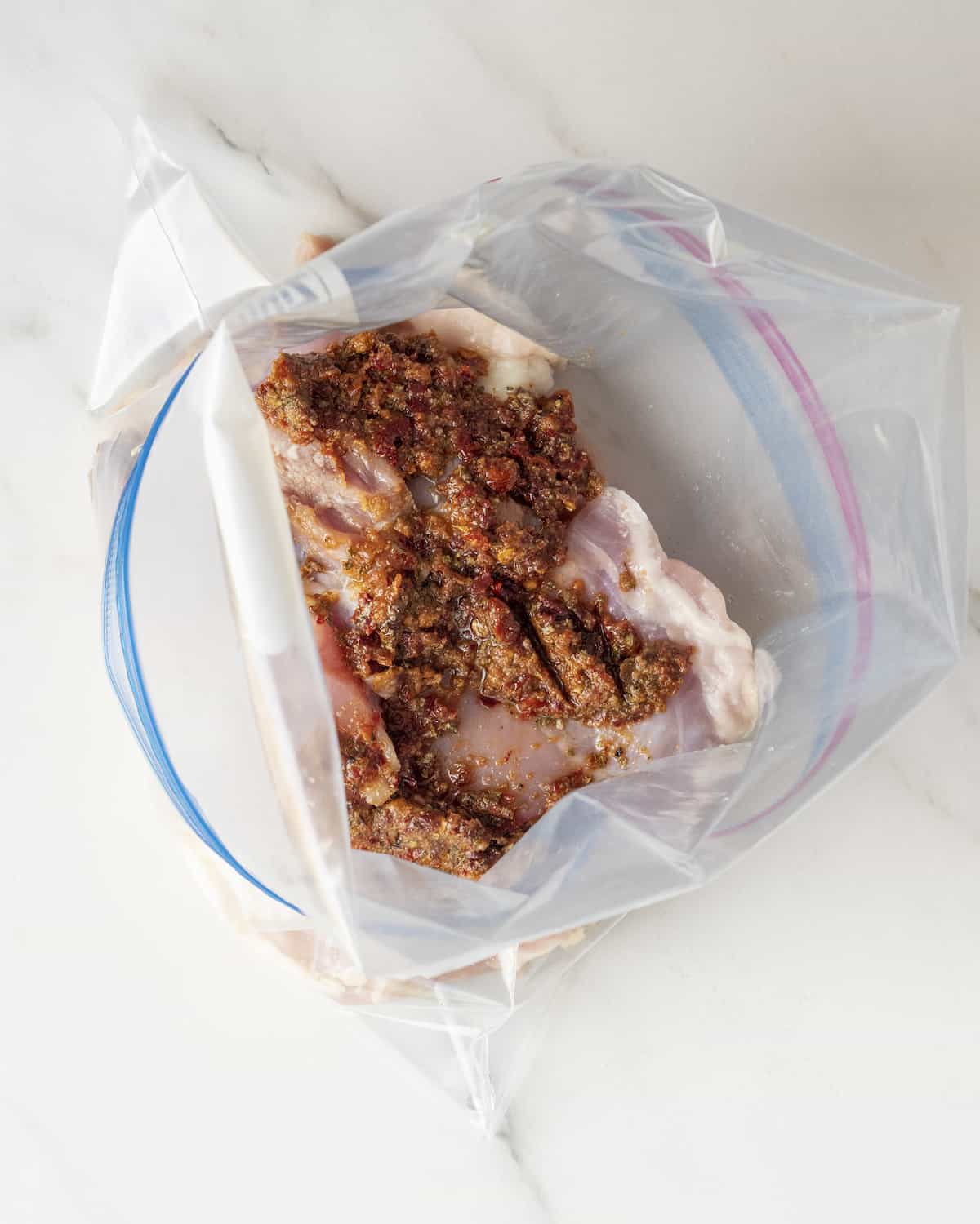 Chicken thighs in a marinade in a large zip top plastic bag.