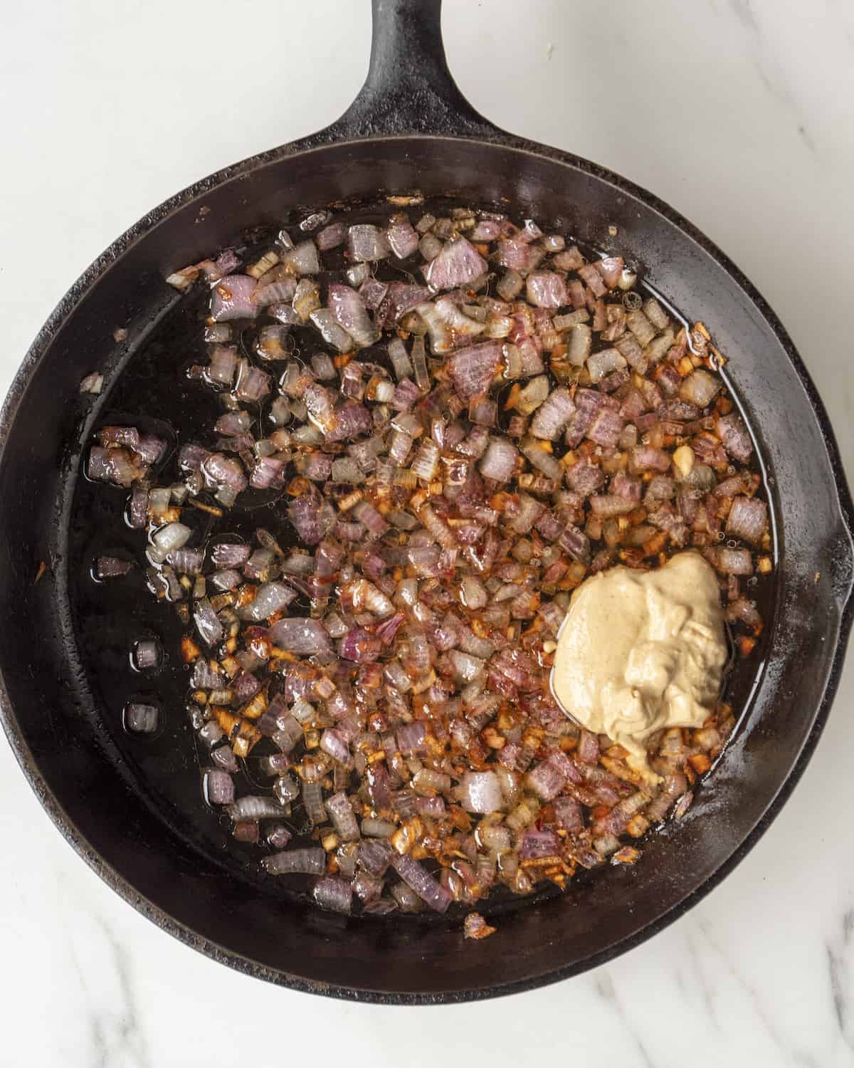 Caramelized red onions in a cast iron skillet with a big dollop of dijon mustard.