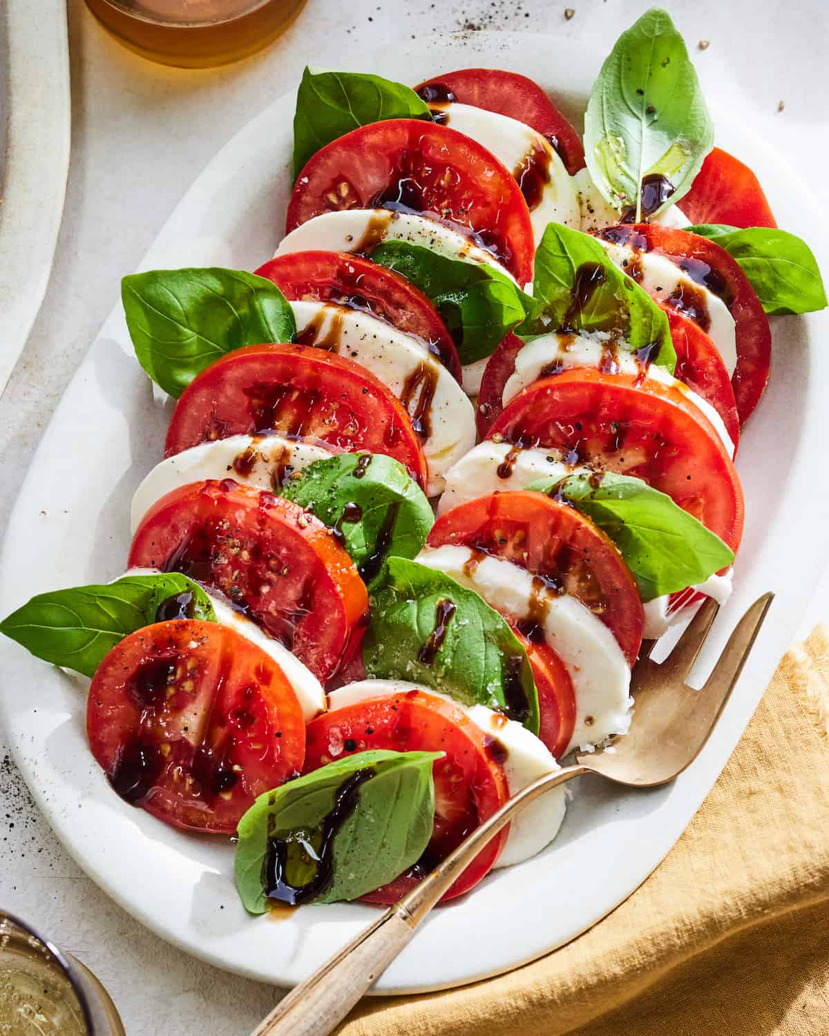 Sliced tomatoes, sliced mozzarella, and basil leaves drizzled with a balsamic glaze.
