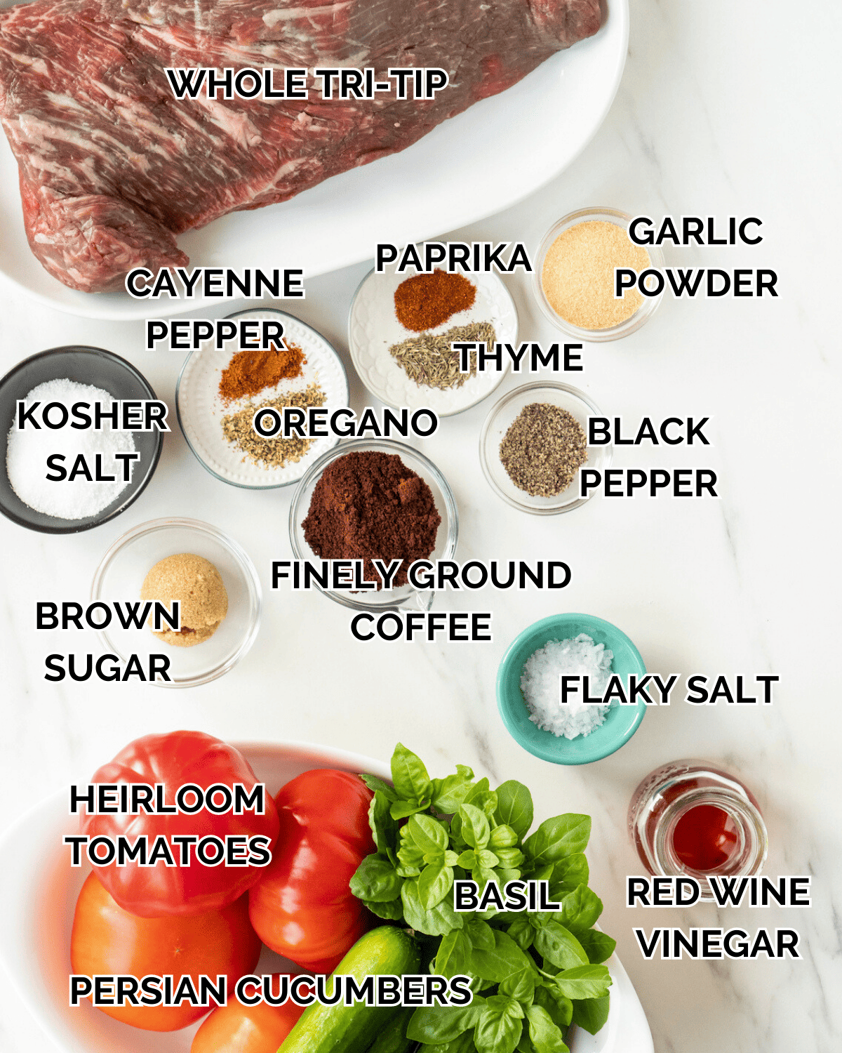 An overhead shot of all the individual ingredients for the recipe.  Ingredients consists of whole tri-tip, cayenne pepper, oregano, salt, paprika, thyme, garlic powder, brown sugar, ground coffee, black pepper, flaky salt, heirloom tomatoes, basil, red wine vinegar, and Persian cucumbers.  