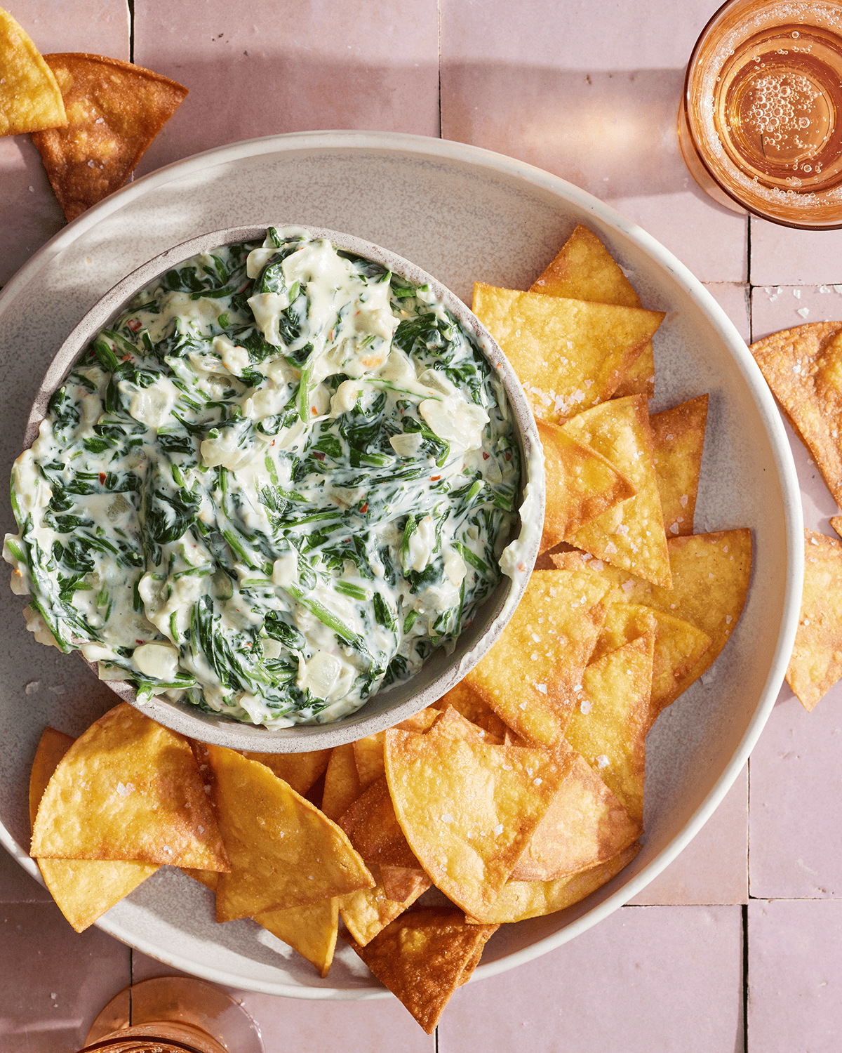 A bowl of Spinach dip next to some homemade tortilla chips.  