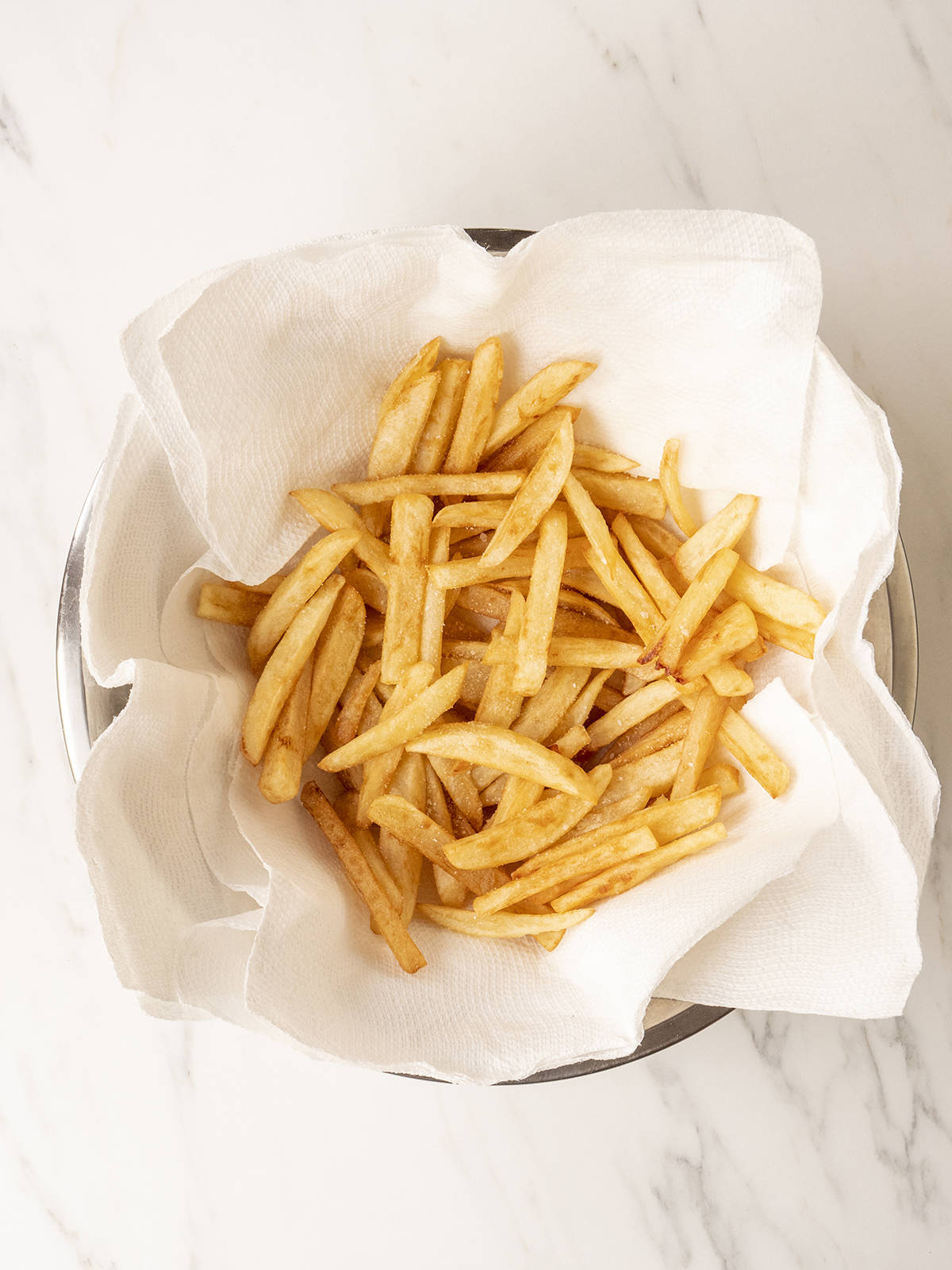 Homemade fries that are drying in a paper towel lined bowl.  