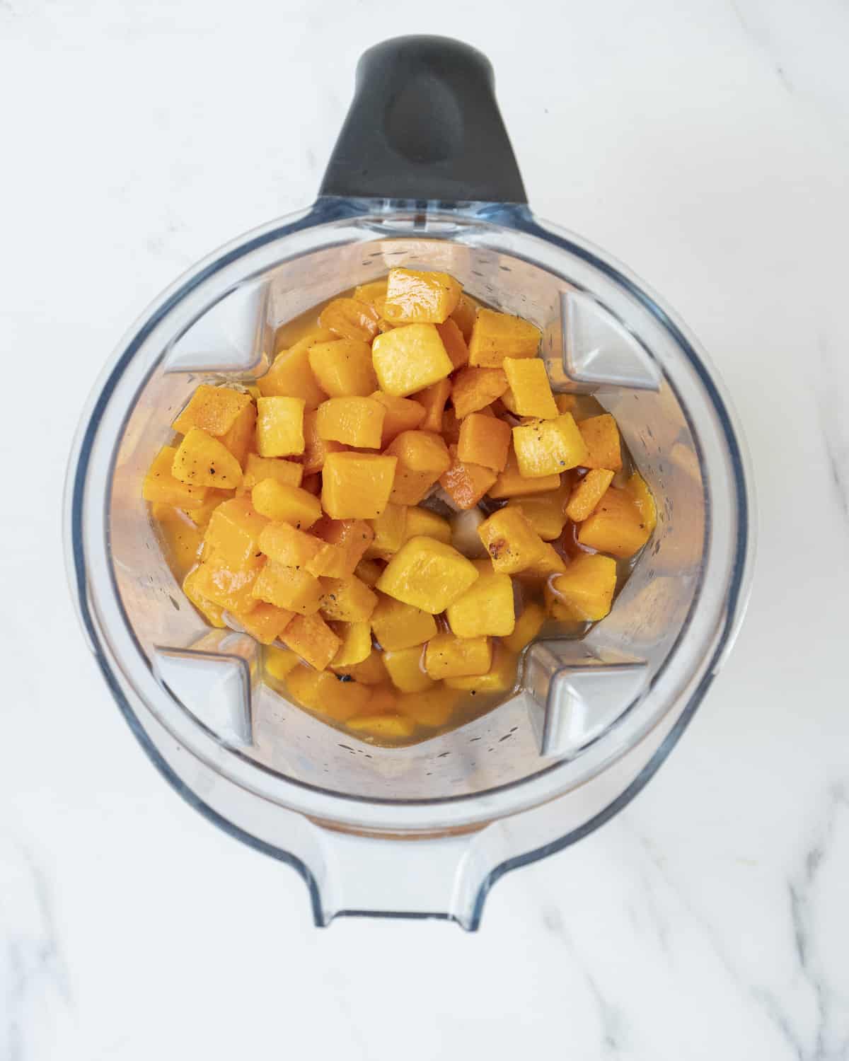 Baked squash that has been cubed sitting inside a blender.  