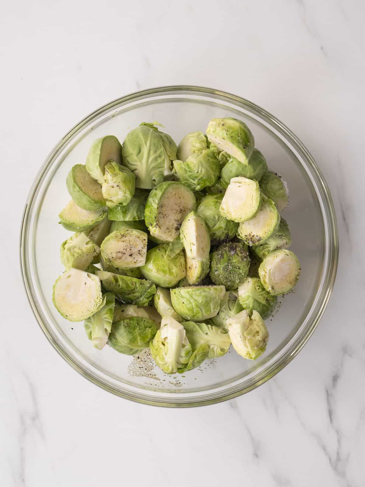 A small mixing bowl with trimmed and halved brussels sprouts.