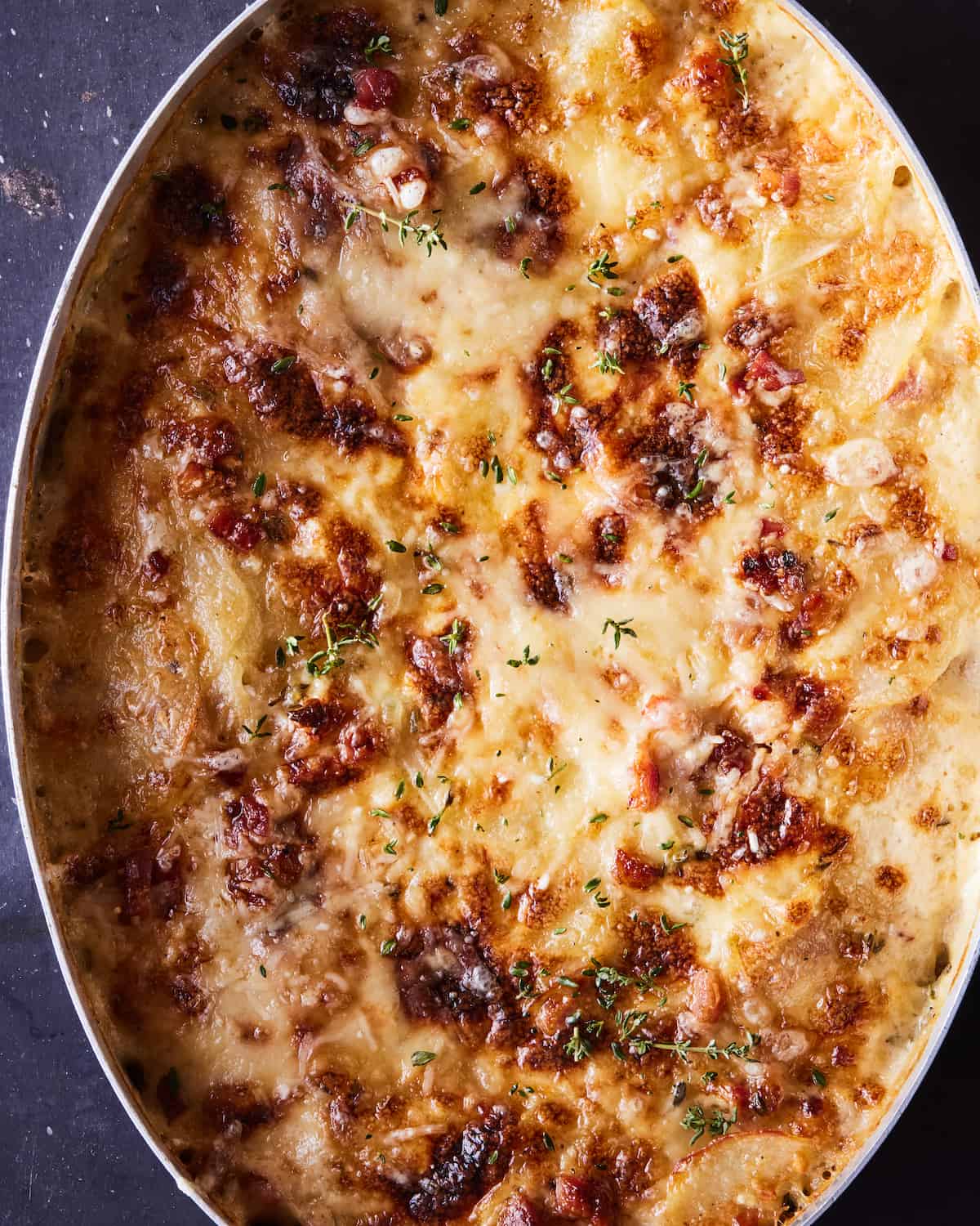 A close up shot of an oval baking dish with potatoes au gratin.