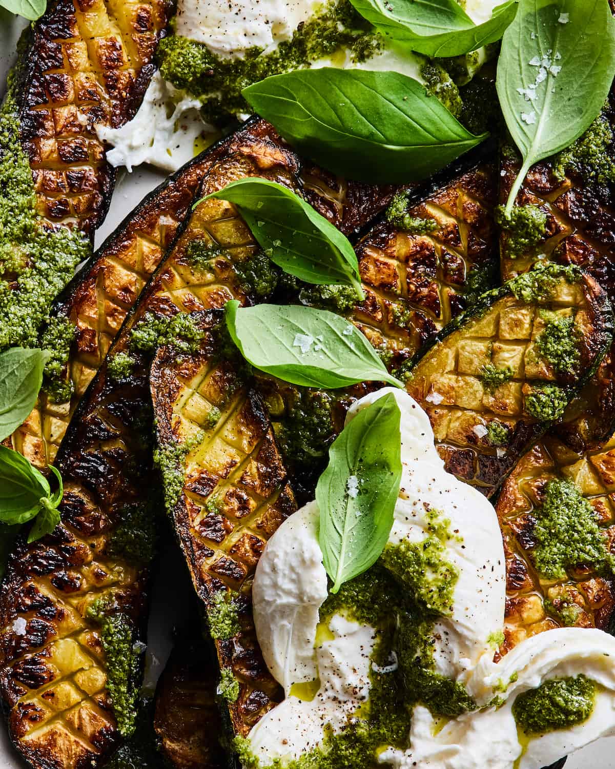 Thomas Keller's Zucchini with Burrata and Pesto close up on a platter with basil leaves