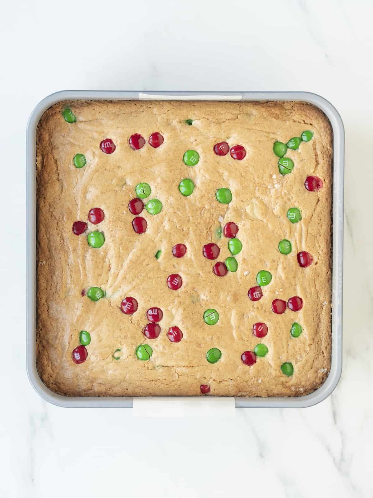 A square baking pan with M&M cookie square baked in it.