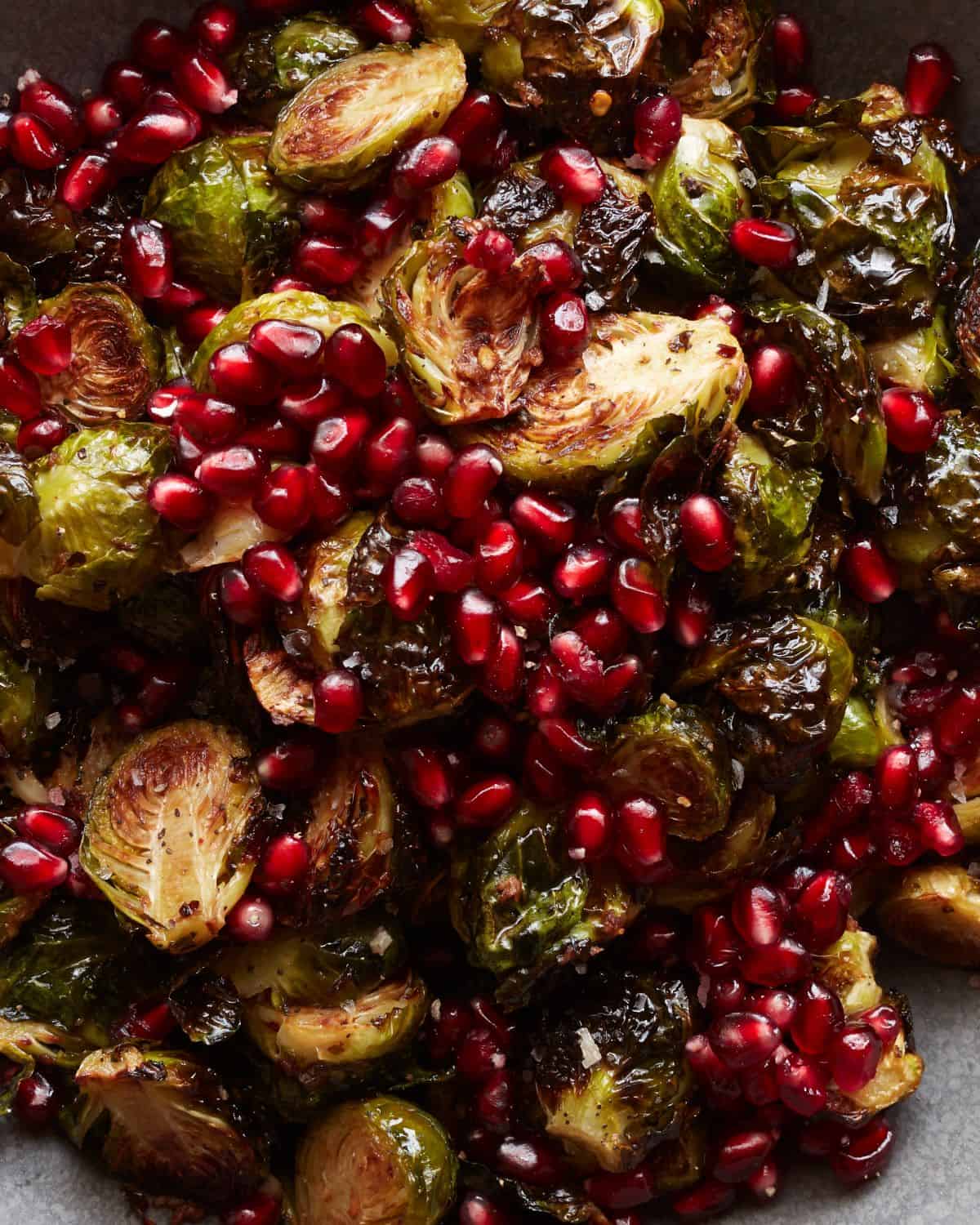 A close up shot of roasted brussels sprouts salad topped with pomegranate seeds.