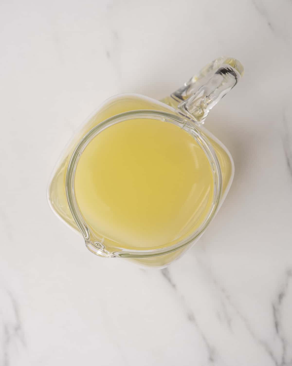 Juiced lemon in glass pitcher on a white countertop