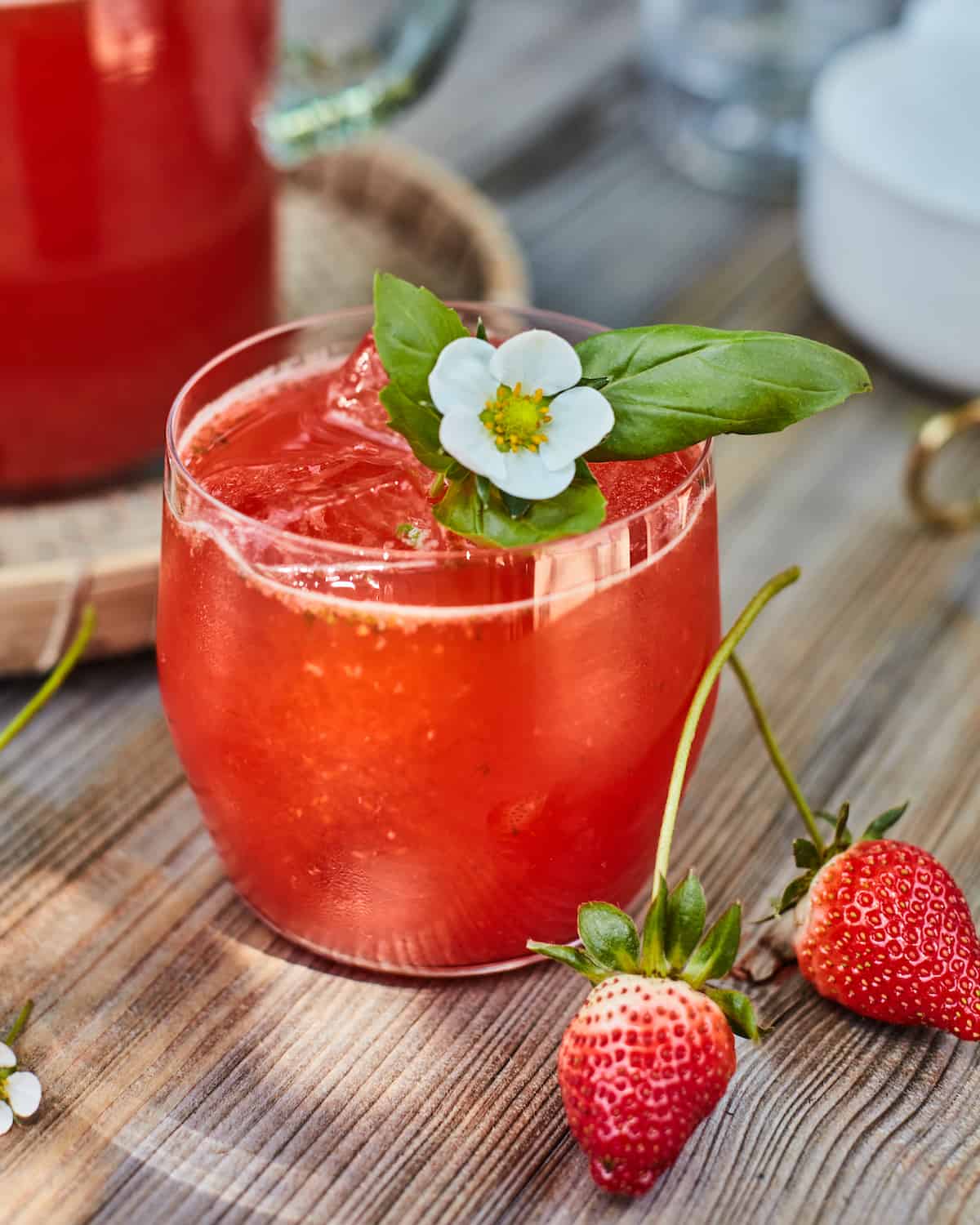 Strawberry basil lemonade sitting on a wooden outdoor table.  