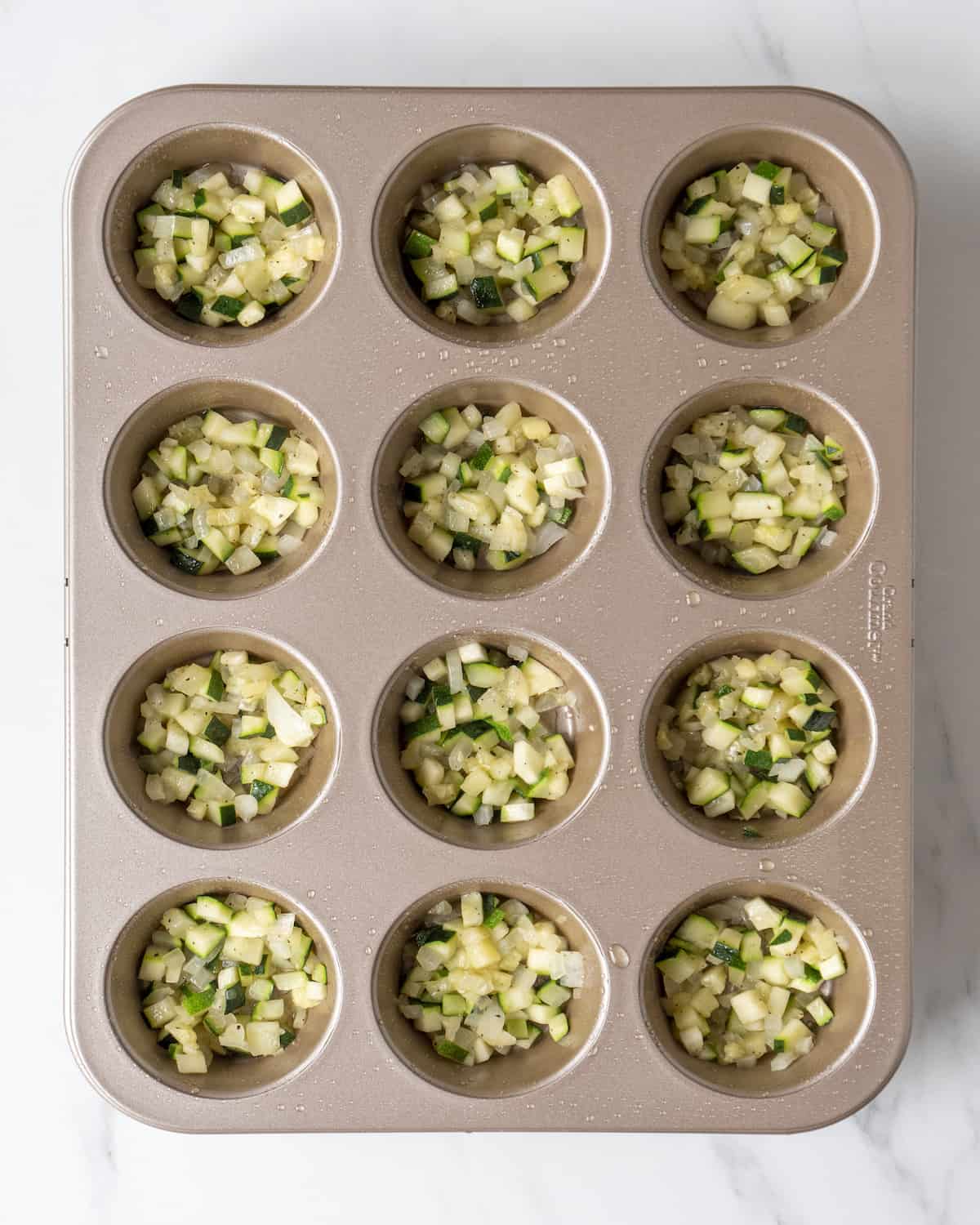 Sautéed zucchini lined in the bottom of a cupcake tin 