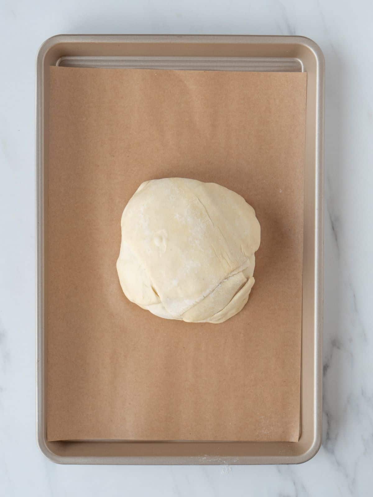 A parchment lined sheet pan with baked brie wrapped in puff pastry.