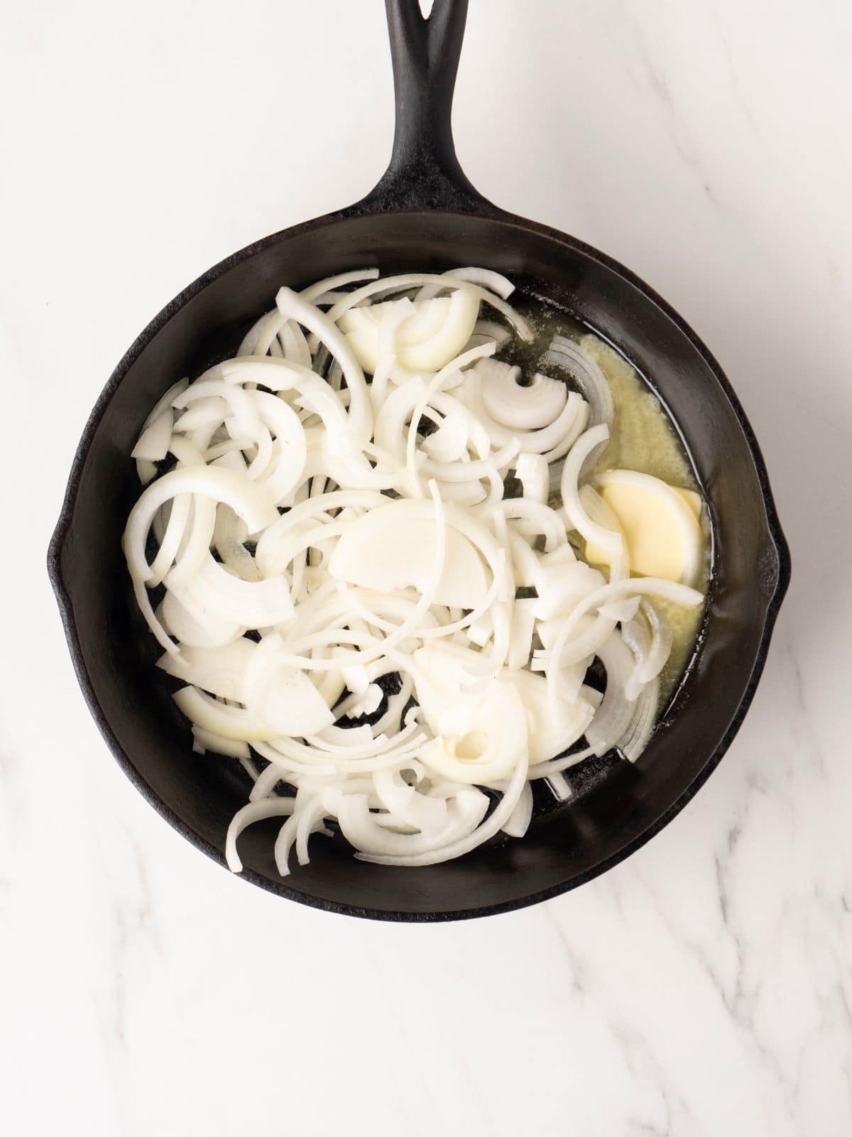 A skillet with sliced yellow onions.