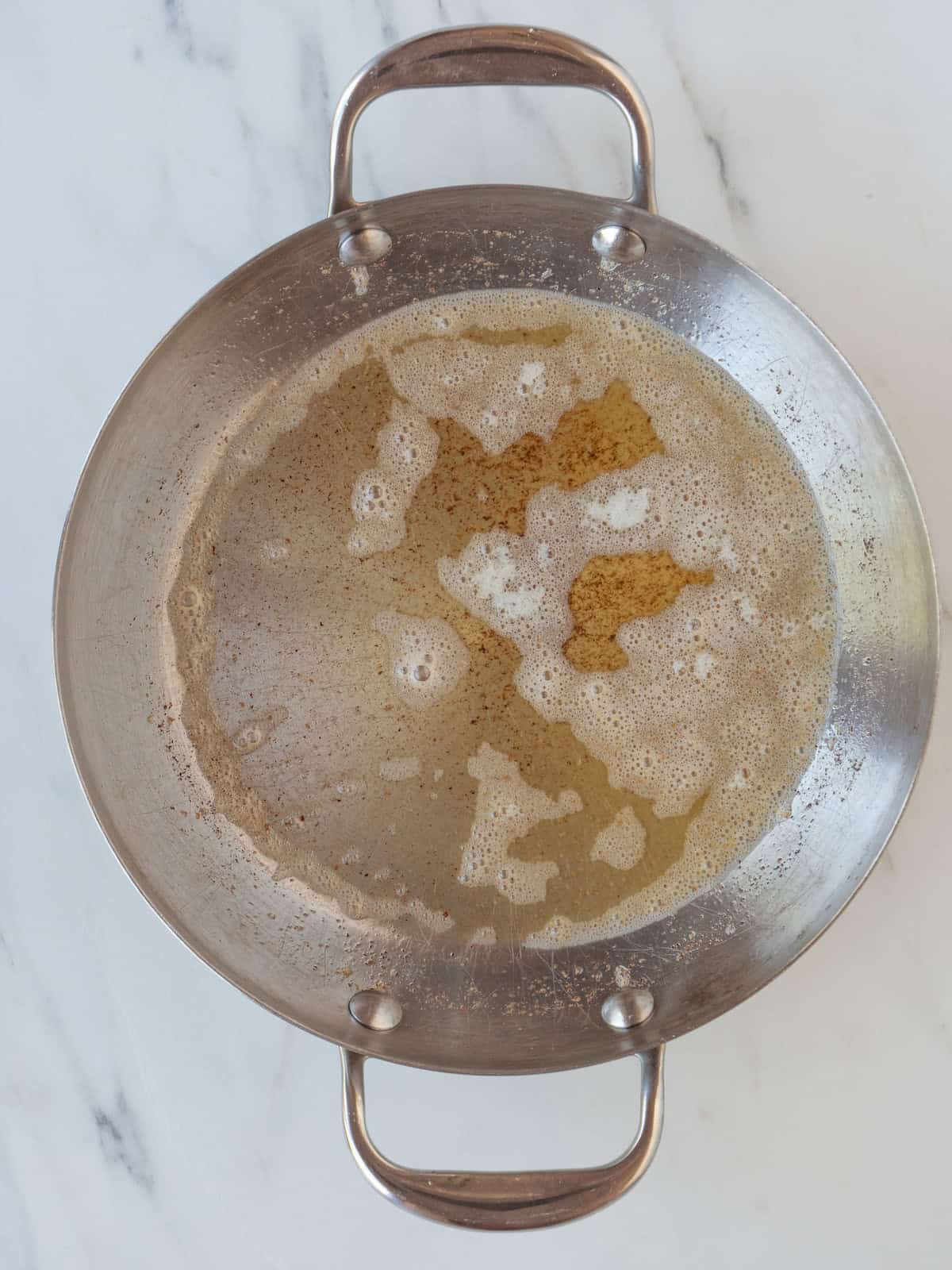 A skillet with molten browned butter, foaming and golden brown.