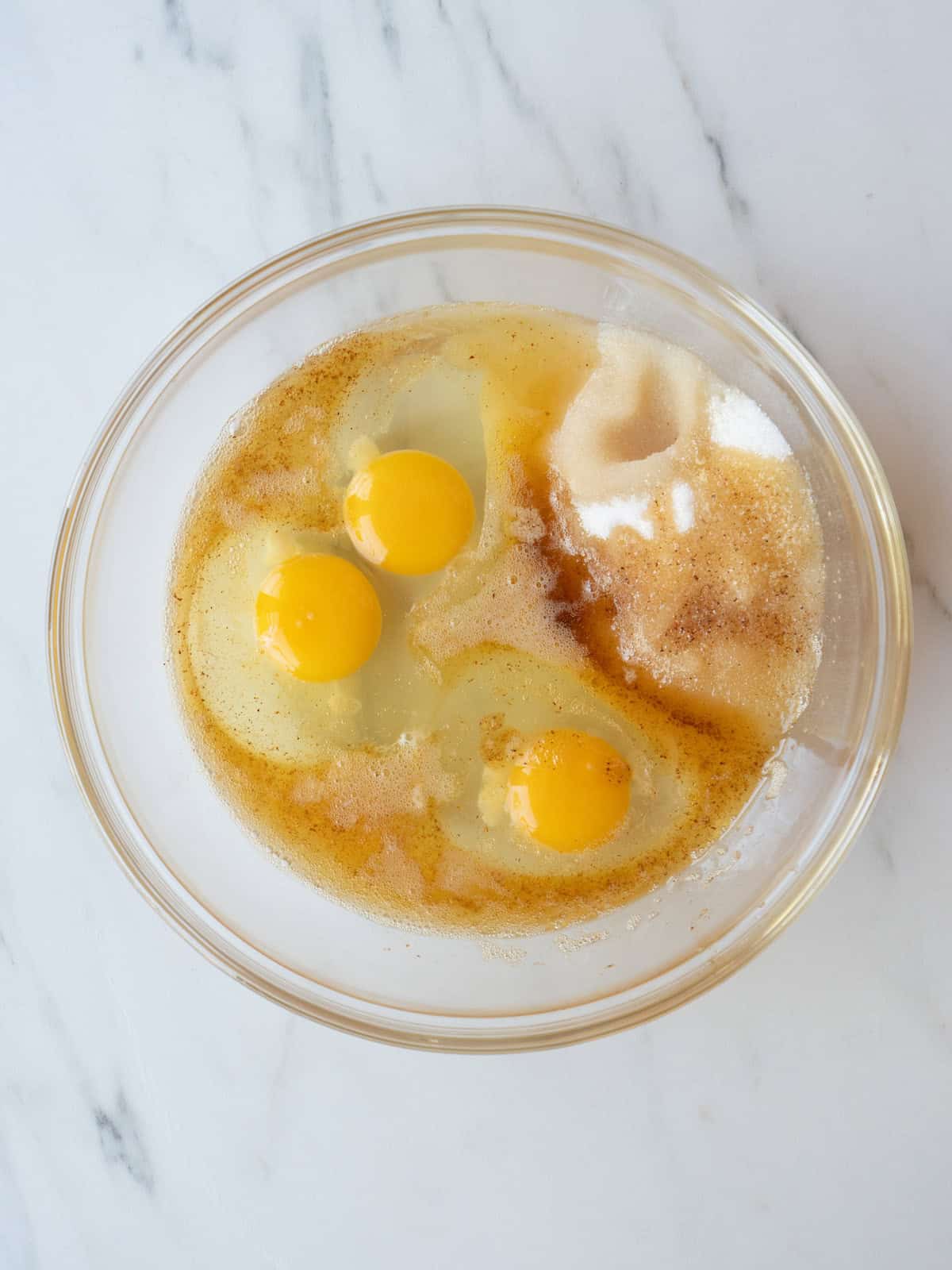 A mixing bowl with corn syrup, eggs, sugar, brown butter, vanilla extract and bourbon.