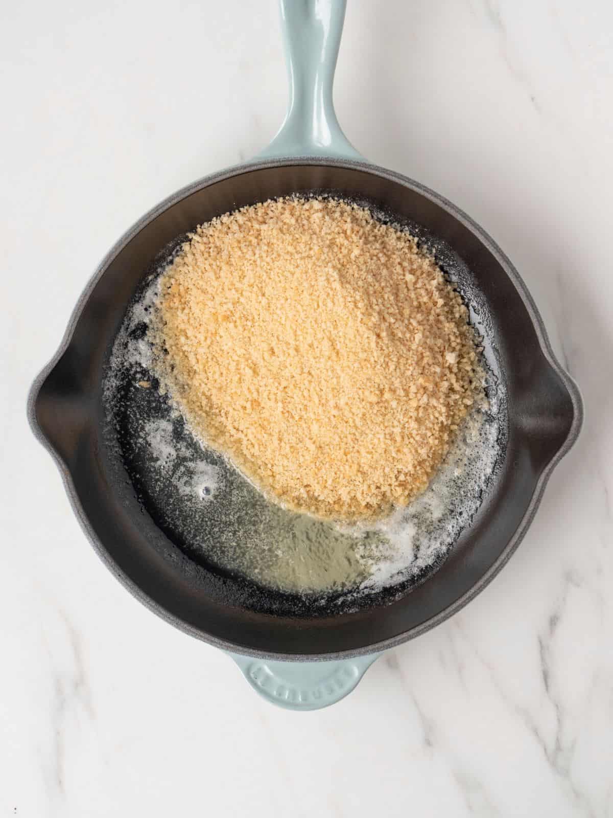 A skillet with butter and panko bread crumbs.