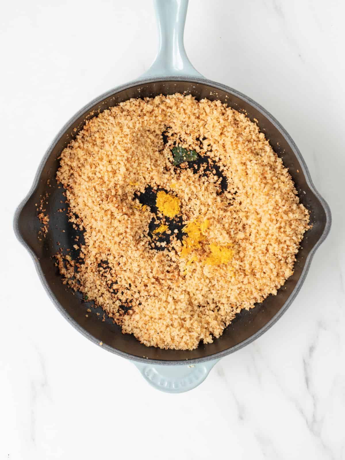 A skillet with panko bread crumbs toasted in butter, with lemon zest added to it.