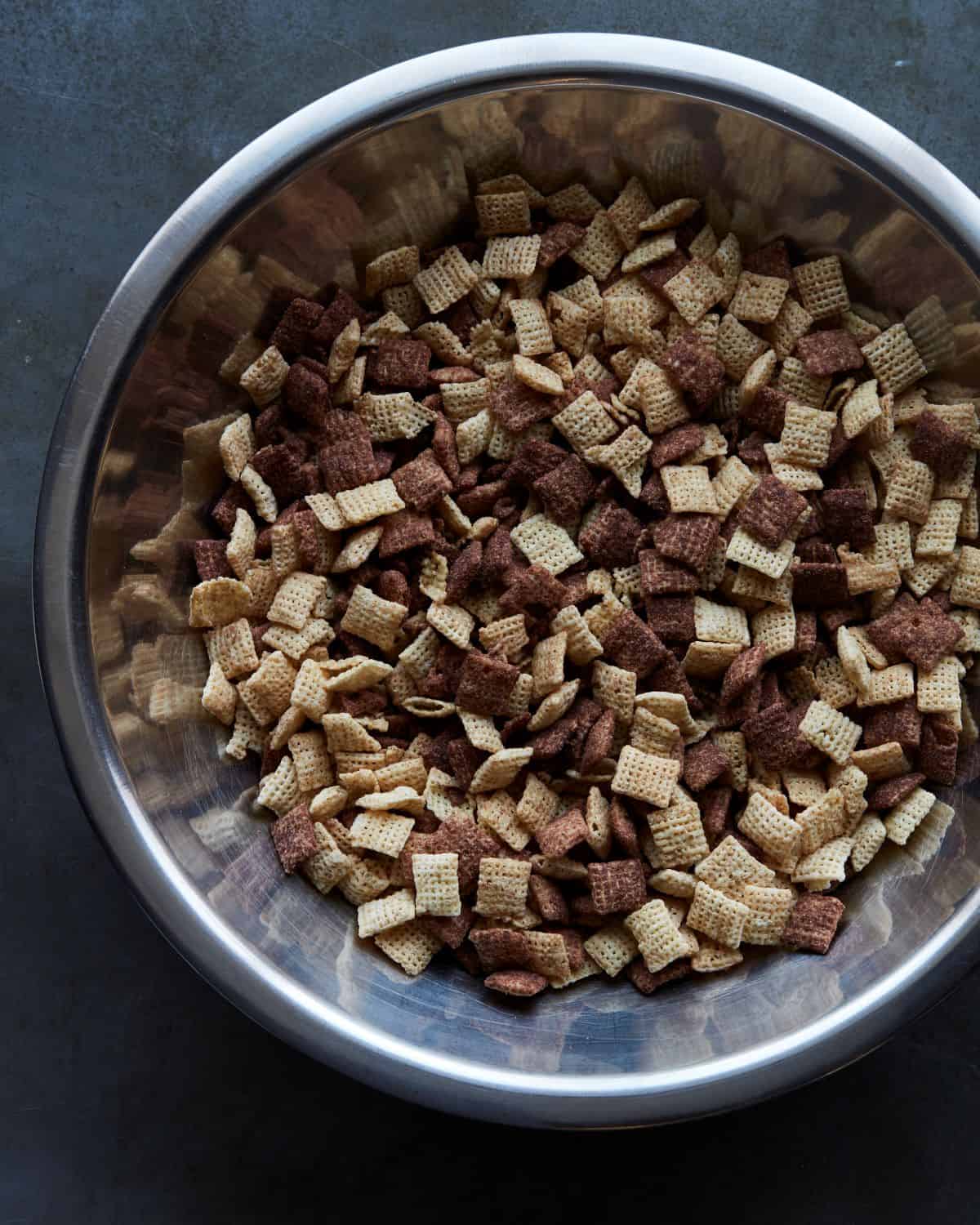 A big steel mixing bowl filled with plain and chocolate Chex.