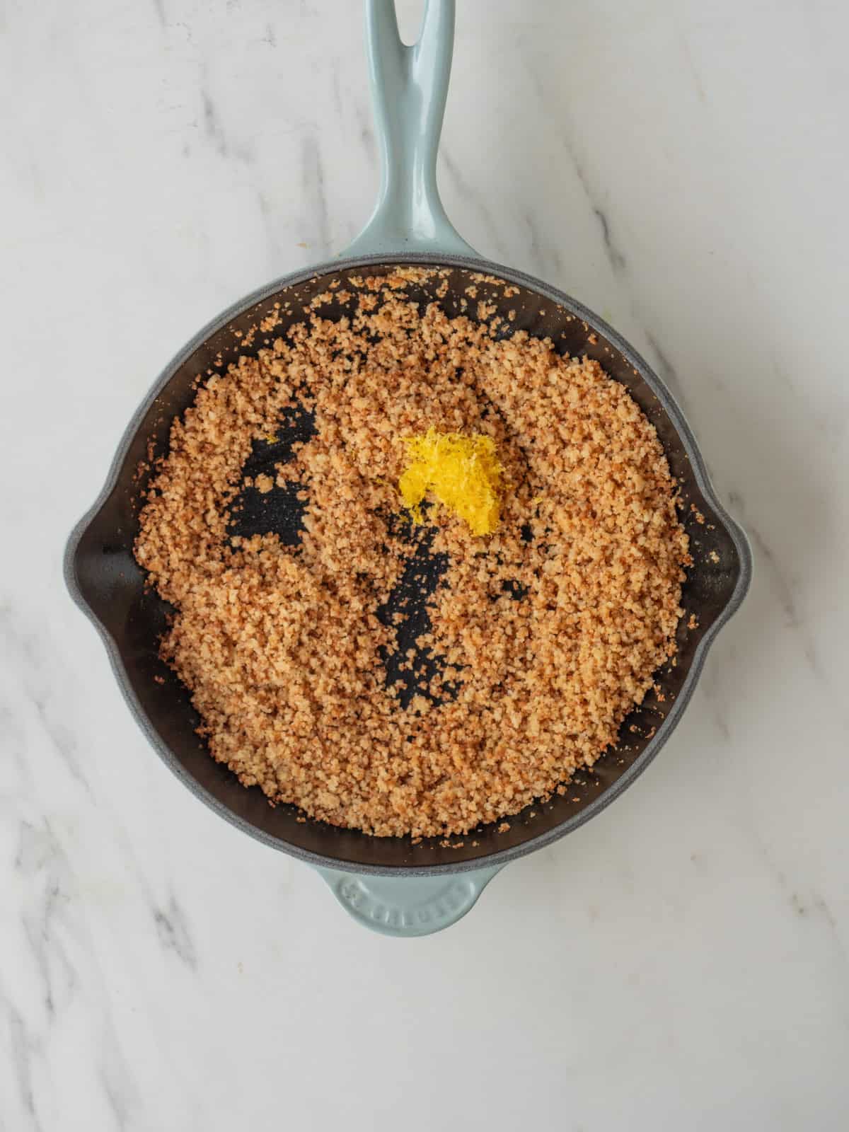 A skillet with breadcrumbs toasted in butter and lemon zest added.