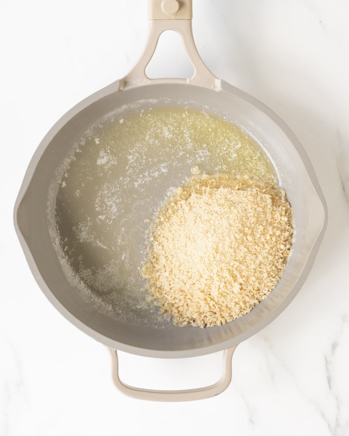 A light pink pan of butter and panko breadcrumbs on a white marbled countertop