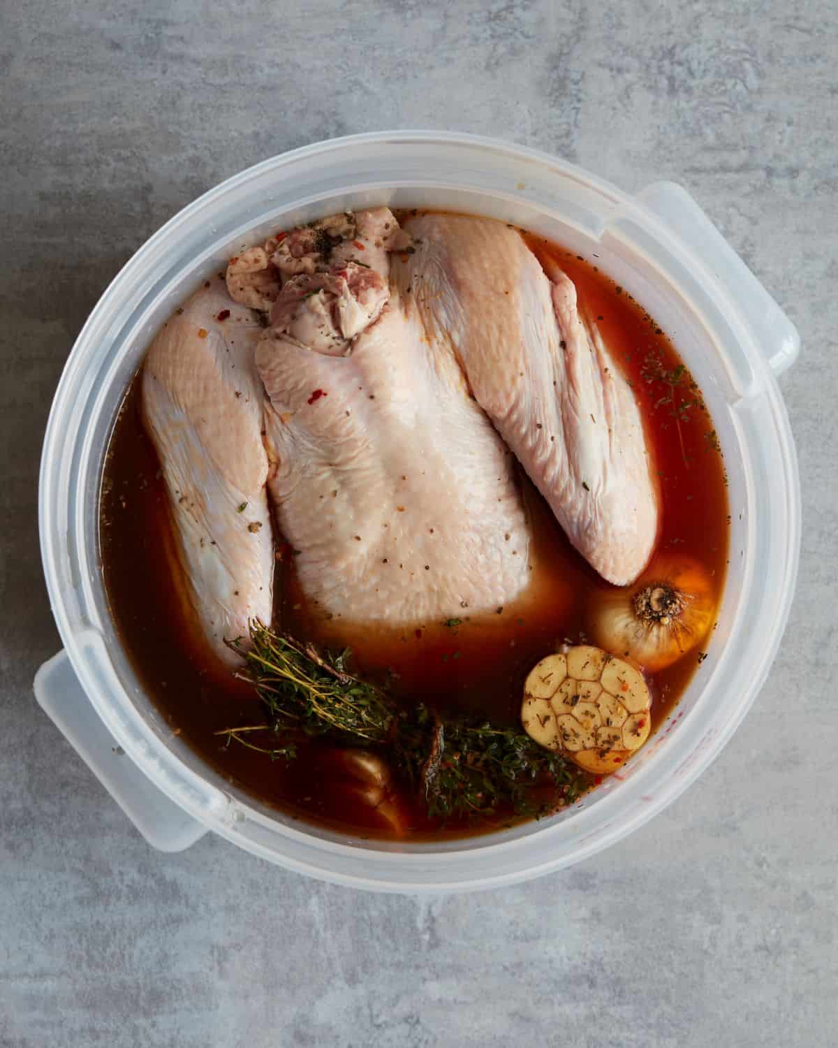 A large plastic container with turkey soaked in a wet brine of water and spices.