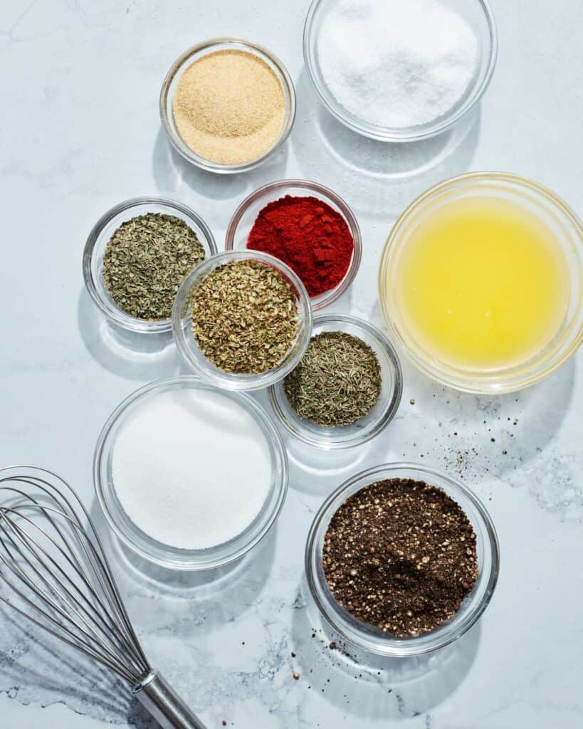 Small glass mixing bowls with spices for dry brine and a whisk.