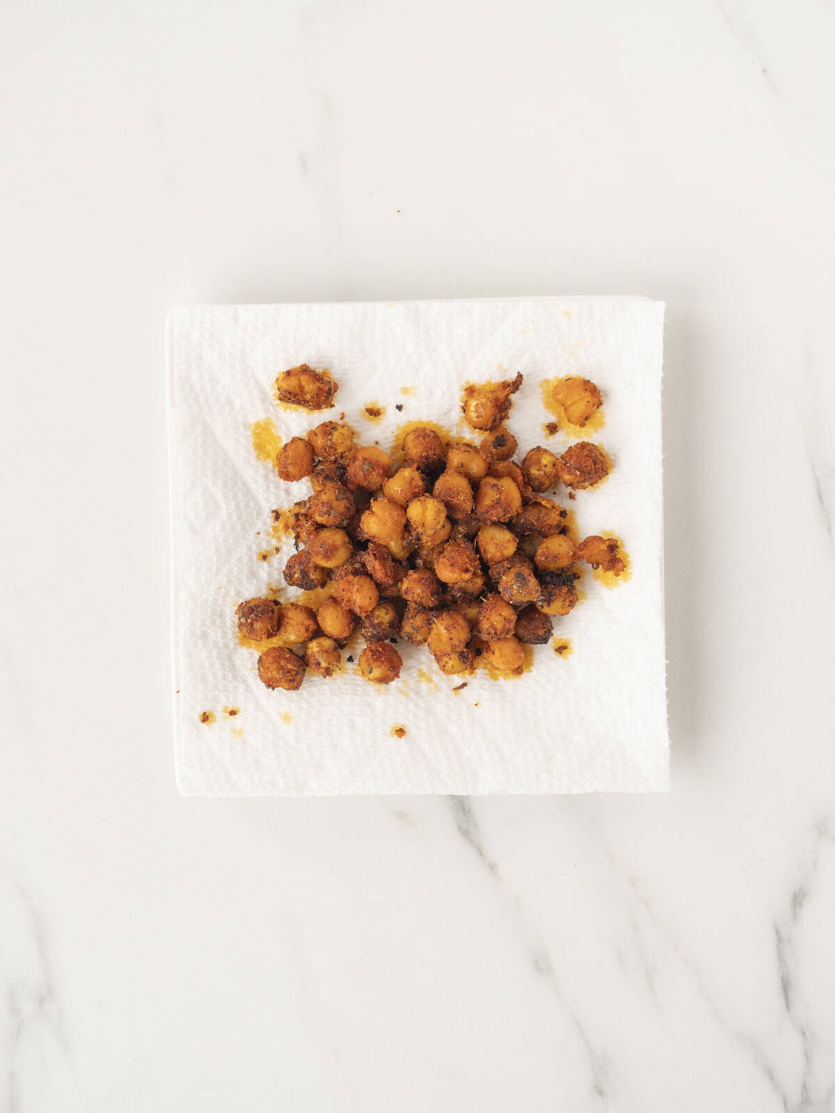 A paper towel with crispy chickpeas that have been just baked in the oven.