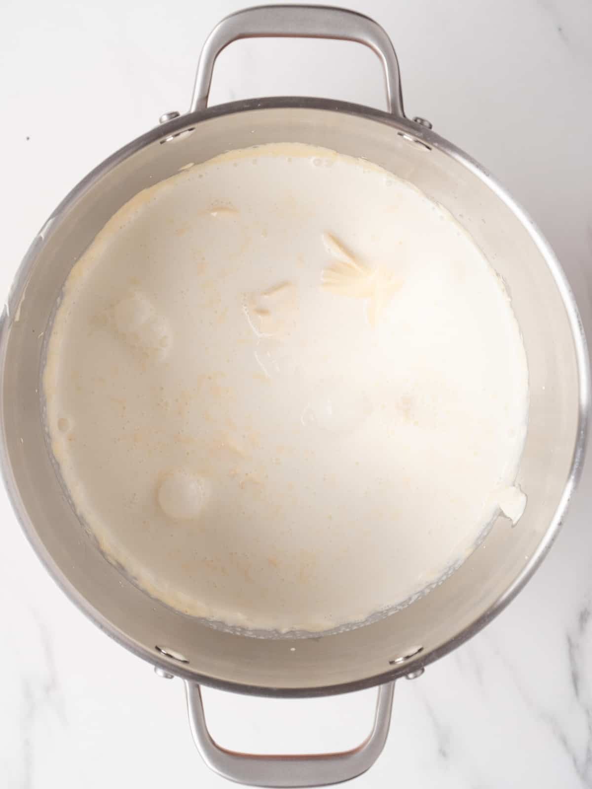 A stand mixer bowl with chilled cream added to the egg-yolk, sugar and mascarpone mixture.