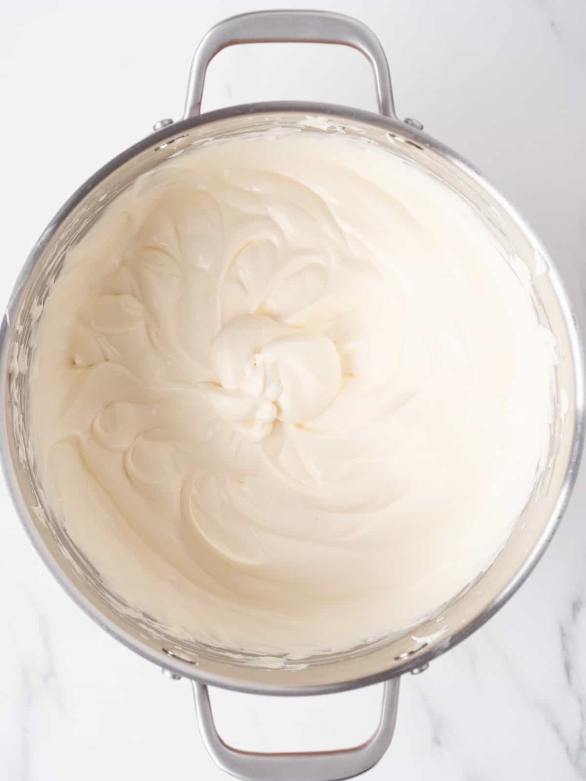 A stand mixer bowl with the whipped mascarpone-cream mixture with soft peaks. 