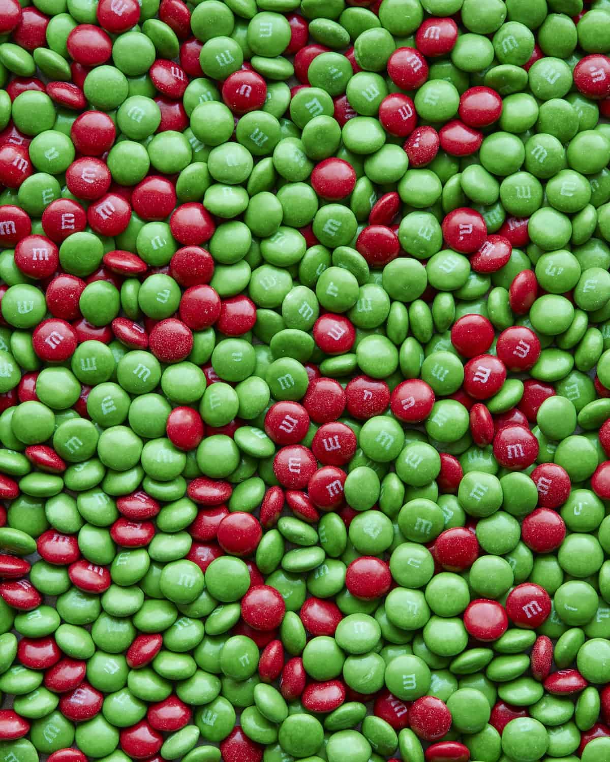 A close-up shot of a flat pile of red and green M&Ms mixed up together.