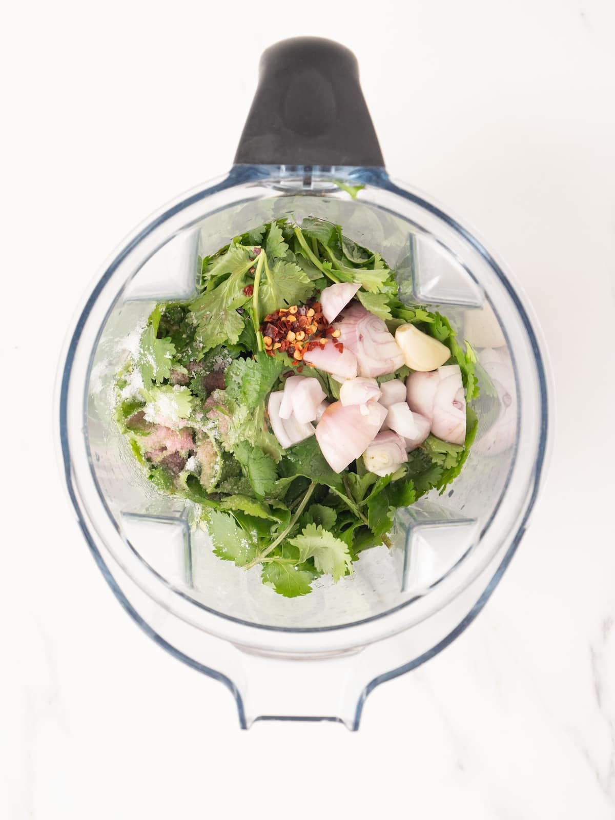 A food processor blender with all the ingredients to make cilantro vinaigrette.