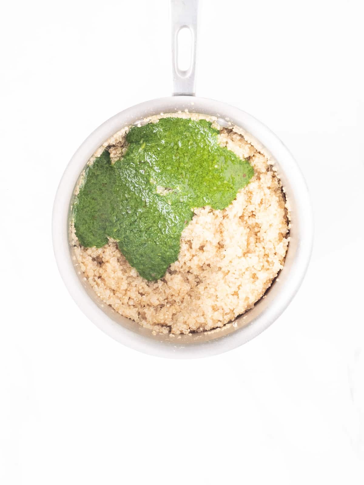 A saucepan with cooked quinoa topped with cilantro vinaigrette.