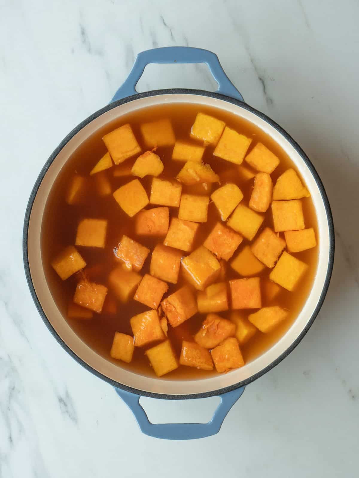 A pot with cubed butternut squash and stock.