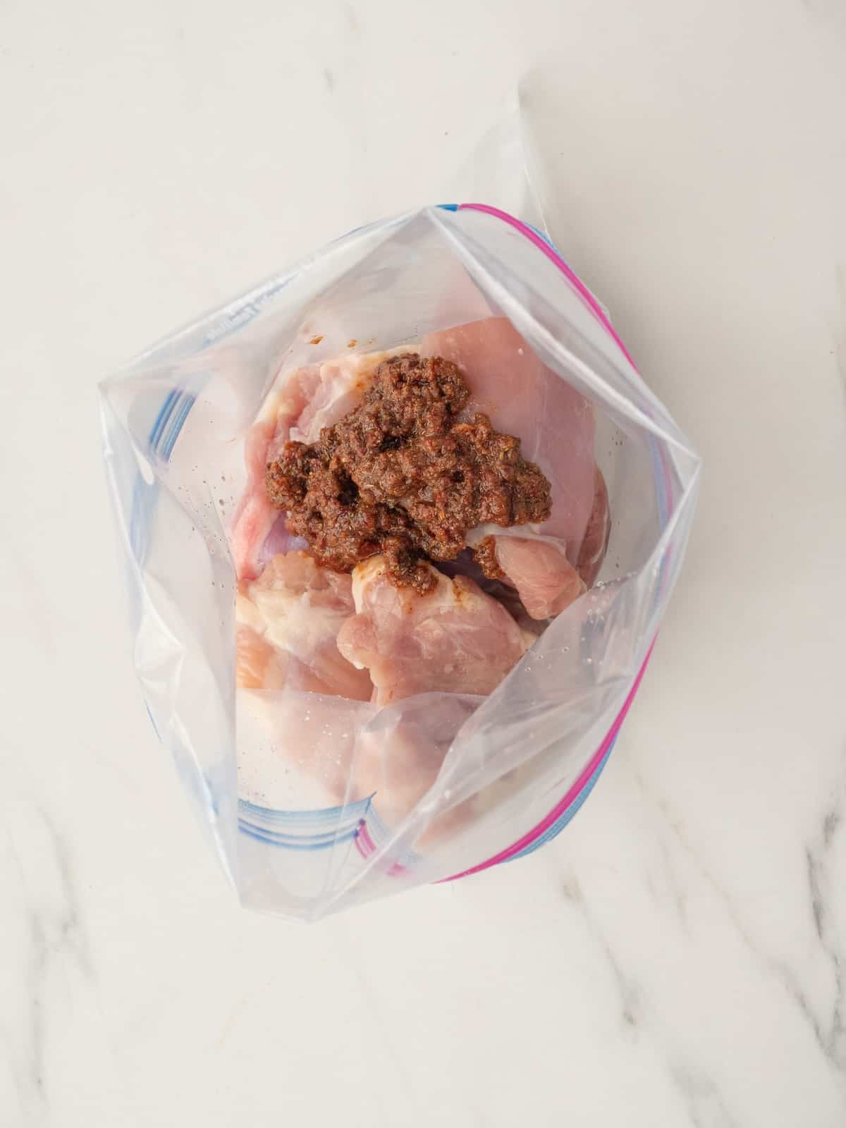 A zip top bag with chicken thighs and marinade mix.