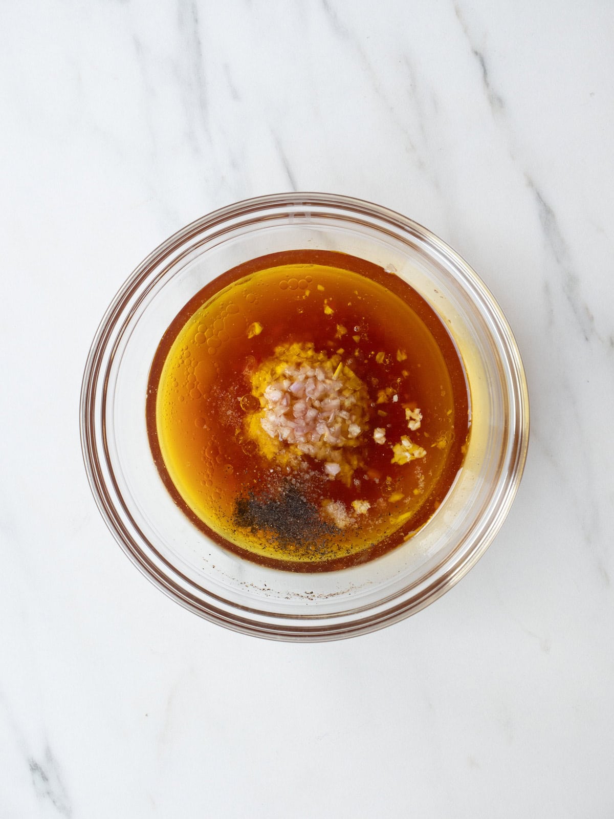 A mixing bowl with all the ingredients to make vinaigrette.