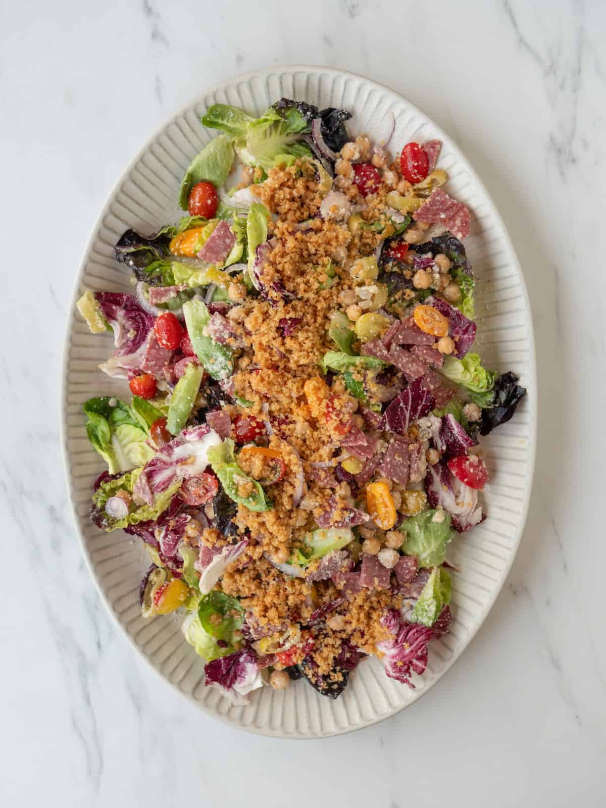 A large platter with radicchio salad topped with shredded cheese and toasted buttered breadcrumbs.