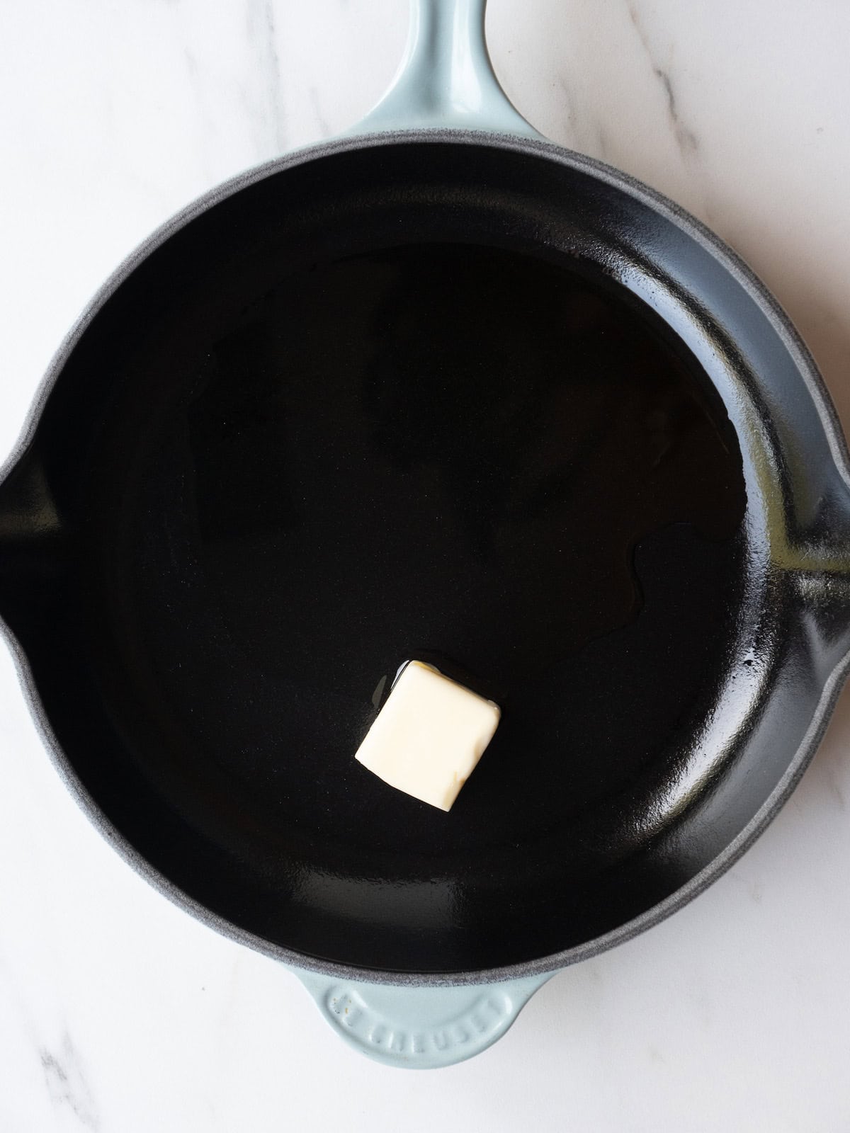 A non-stick skillet with butter and olive oil to toast breadcrumbs.