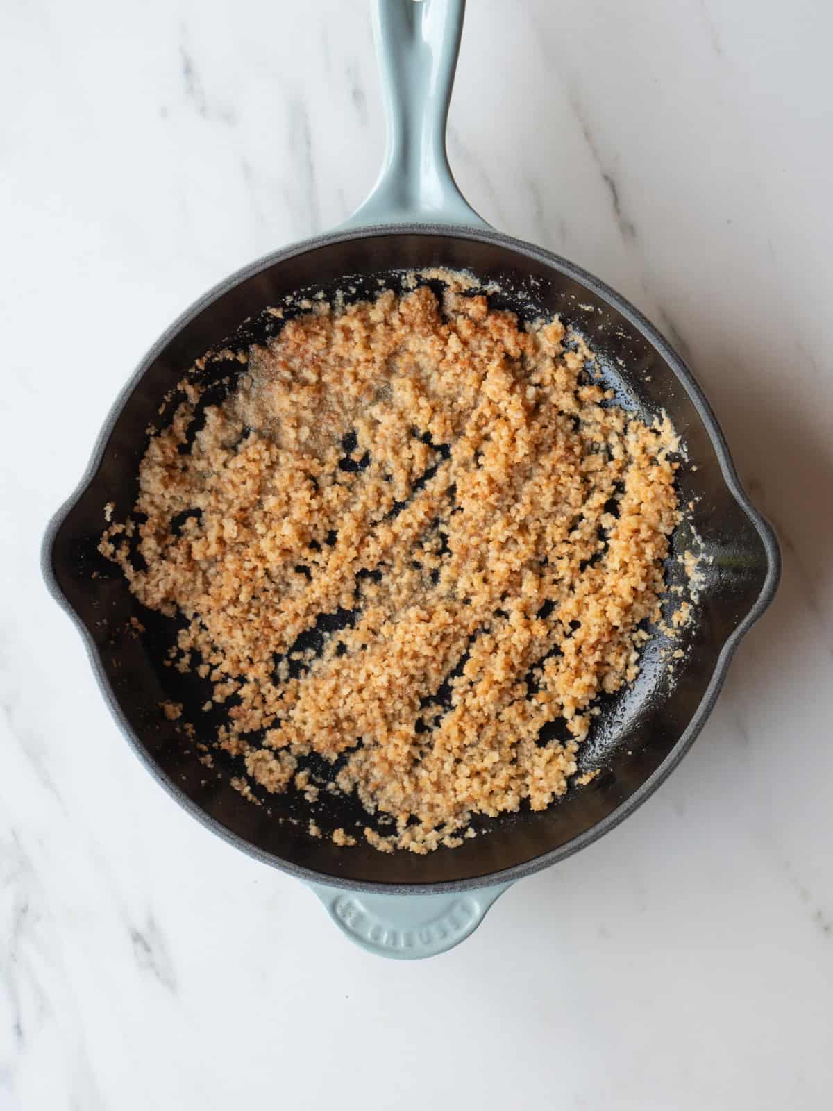 A non-stick skillet with breadcrumbs being toasted to top the radicchio salad.