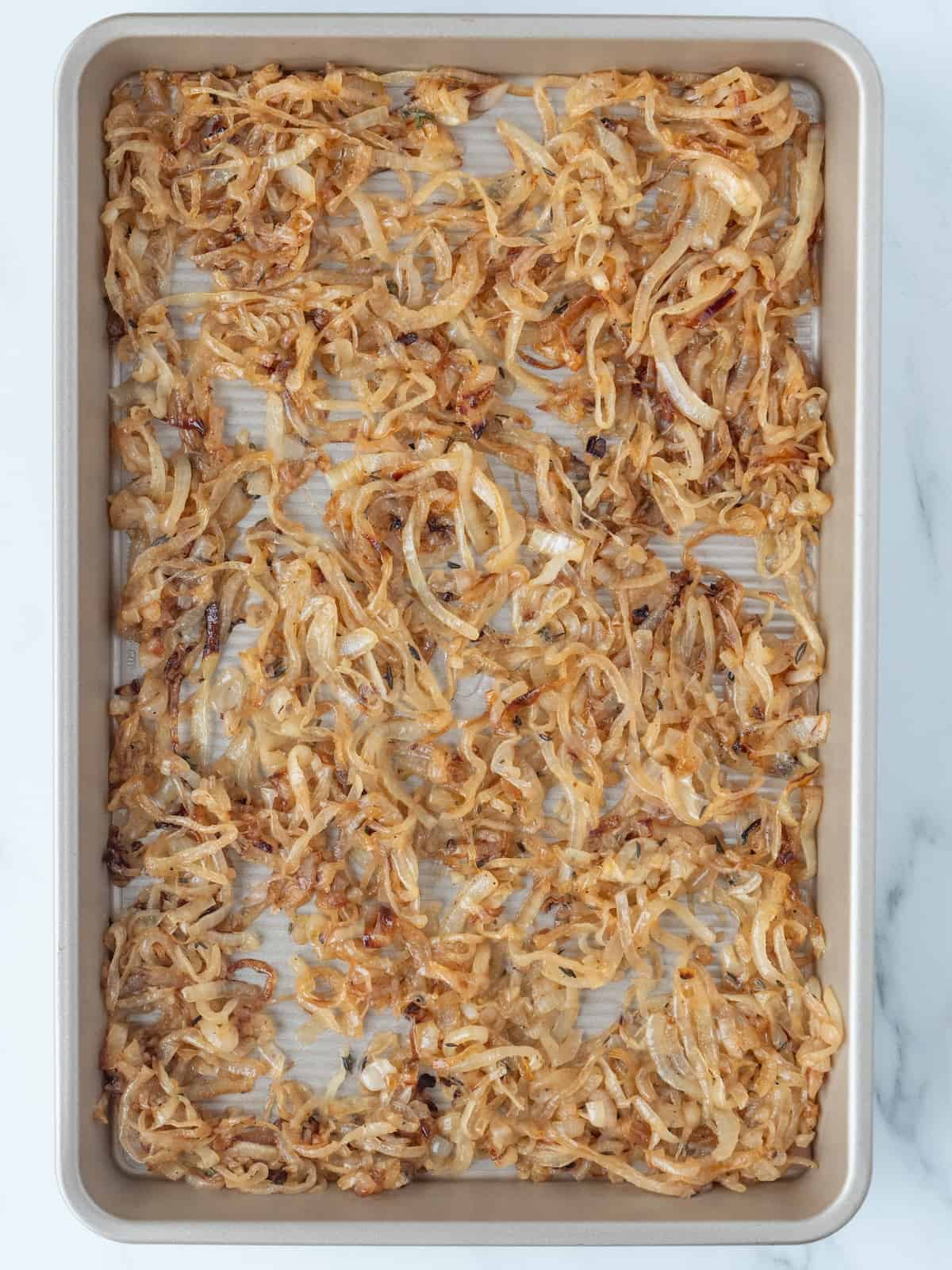 A baking sheet of roasted onions and garlic.