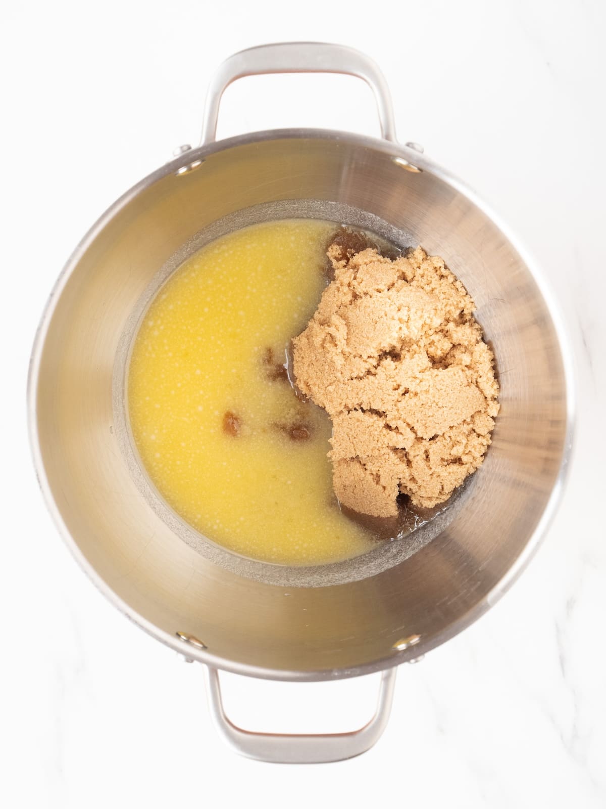 A stand mixer bowl with melted butter and brown sugar.