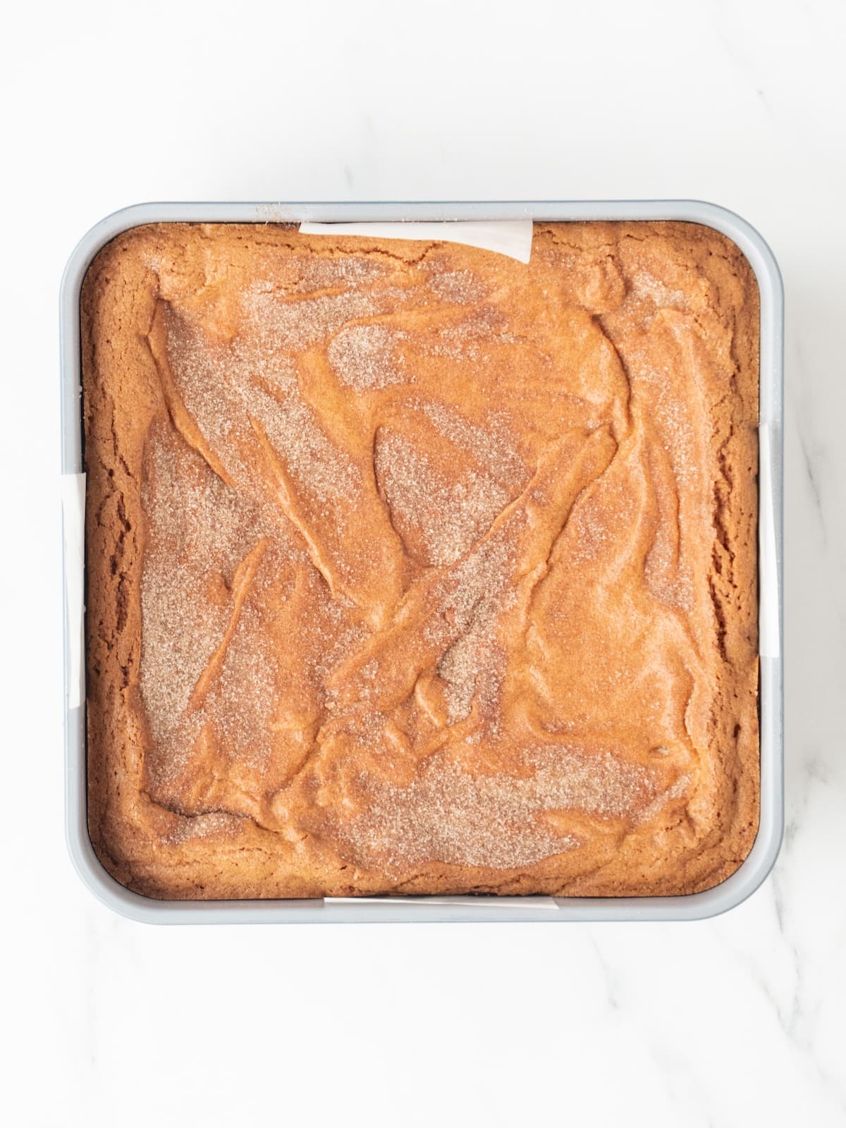 A 9x9 inch baking pan with snickerdoodle blondie brownie baked and fresh out of the oven.