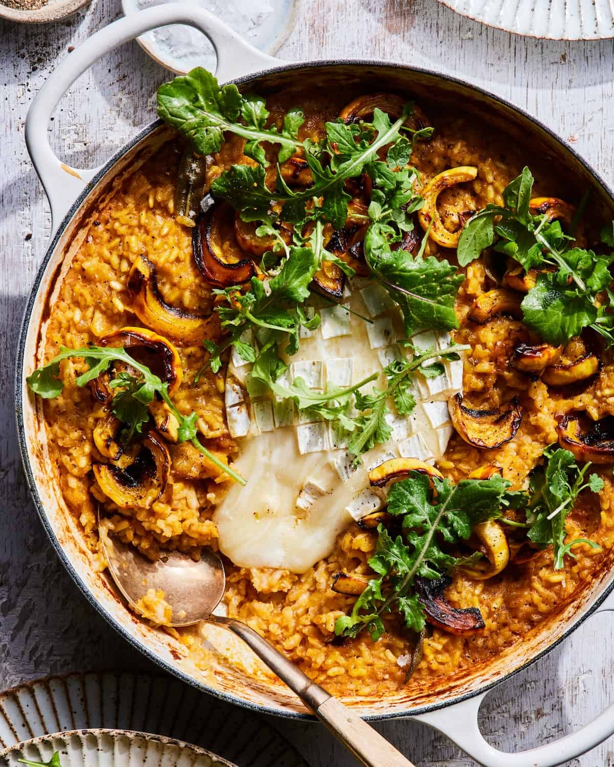 Baked Squash Risotto in a low braiser with gooey cheese in the center and dressed arugula 