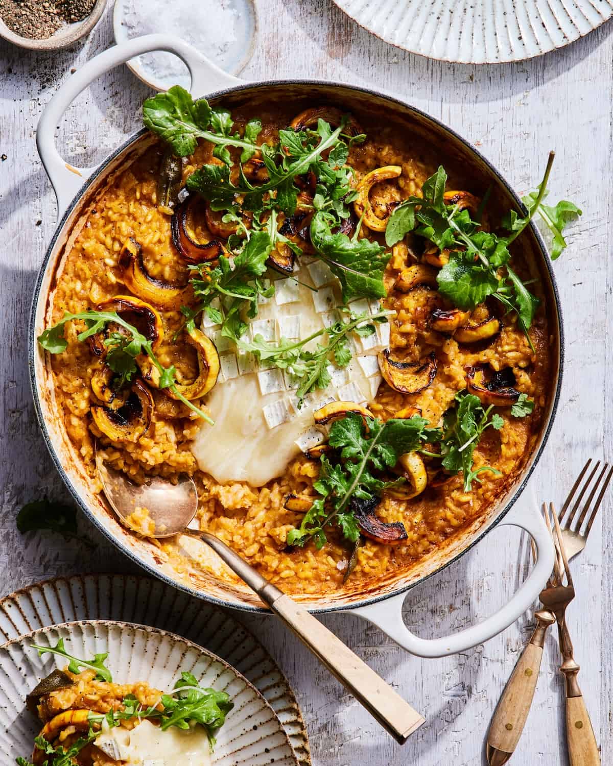 Baked Squash Risotto in a low braiser with gooey cheese in the center and dressed arugula 