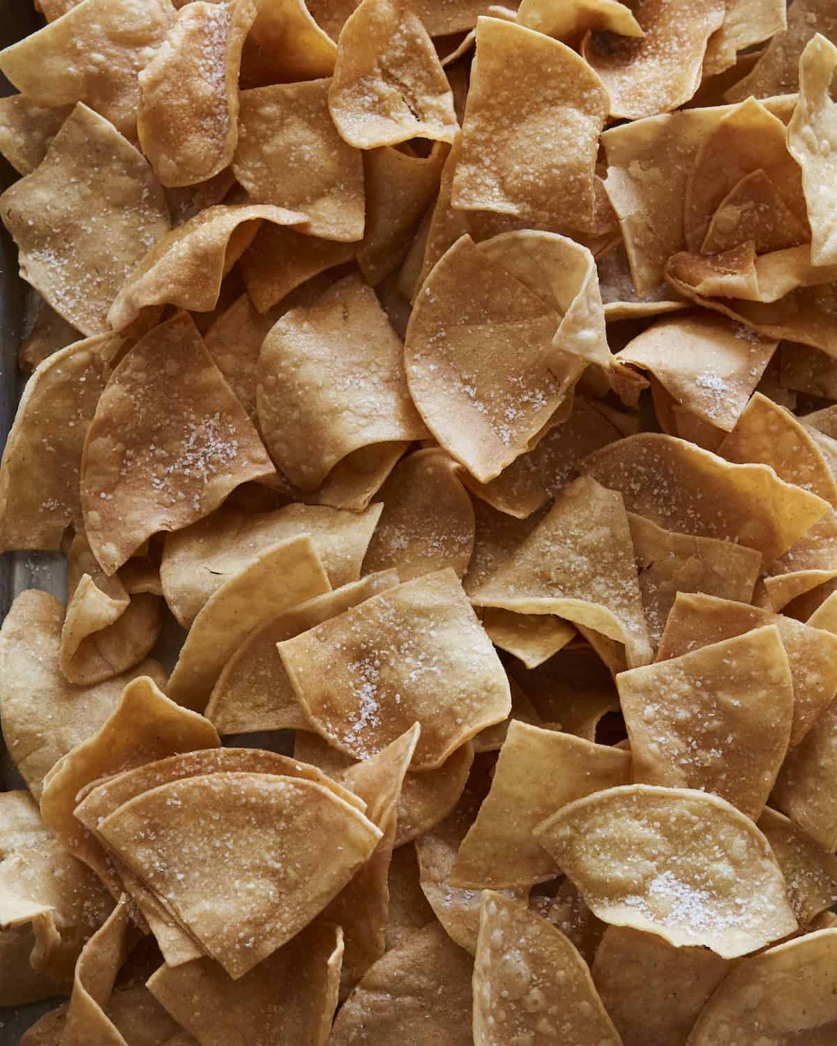 A closeup overhead shot of tortilla chips, tossed with salt.