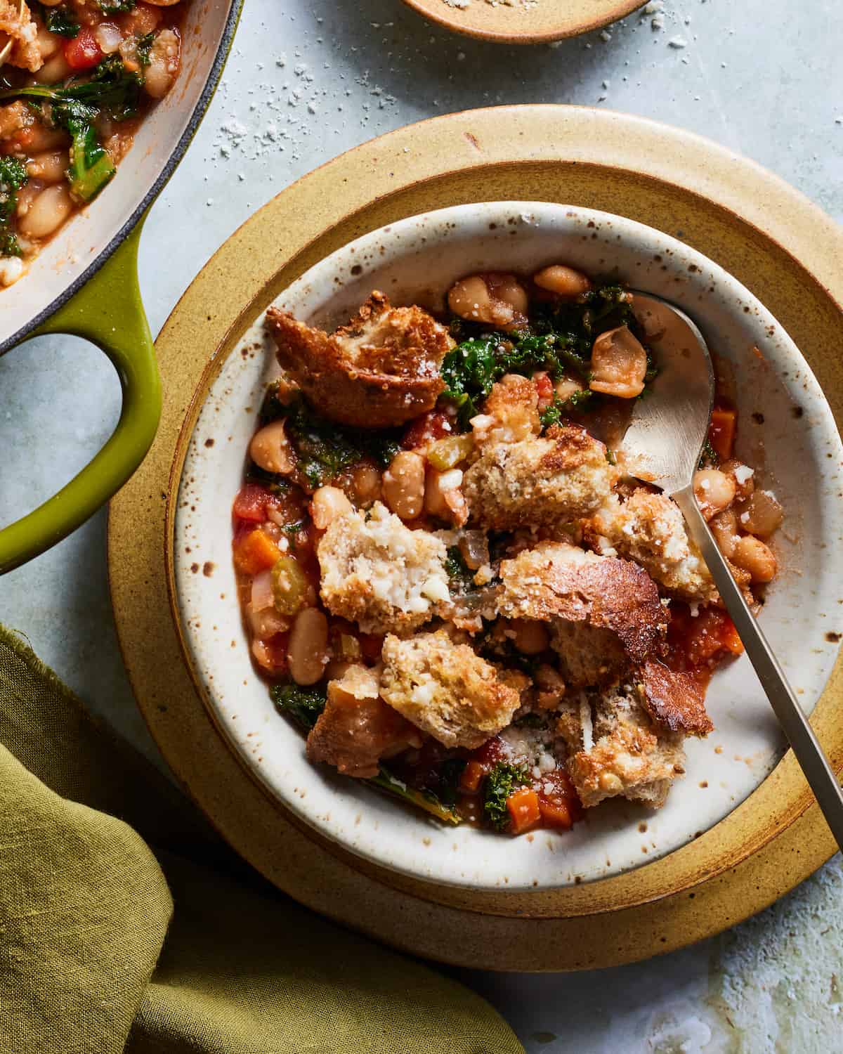 Ribollita in a serving bowl with crusty bread on top and parmesan cheese
