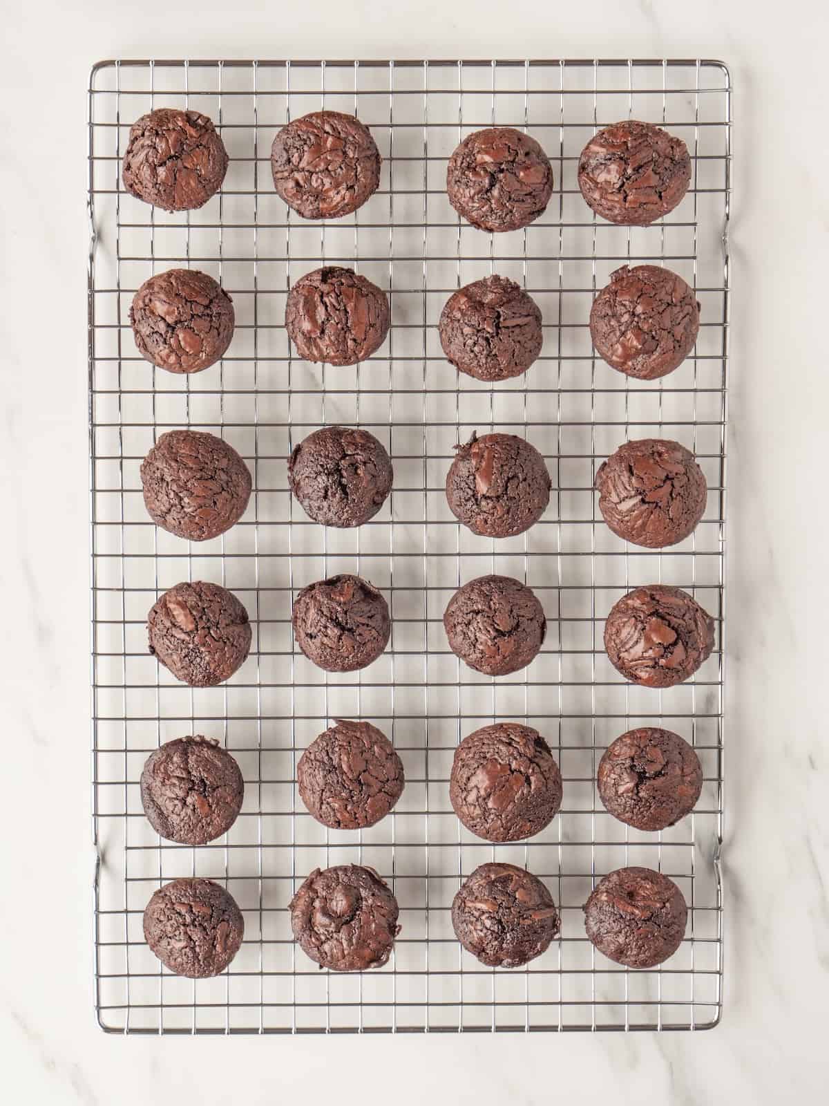 A wire rack with crinkle top brownie bites just baked and removed from pan to be cooled.