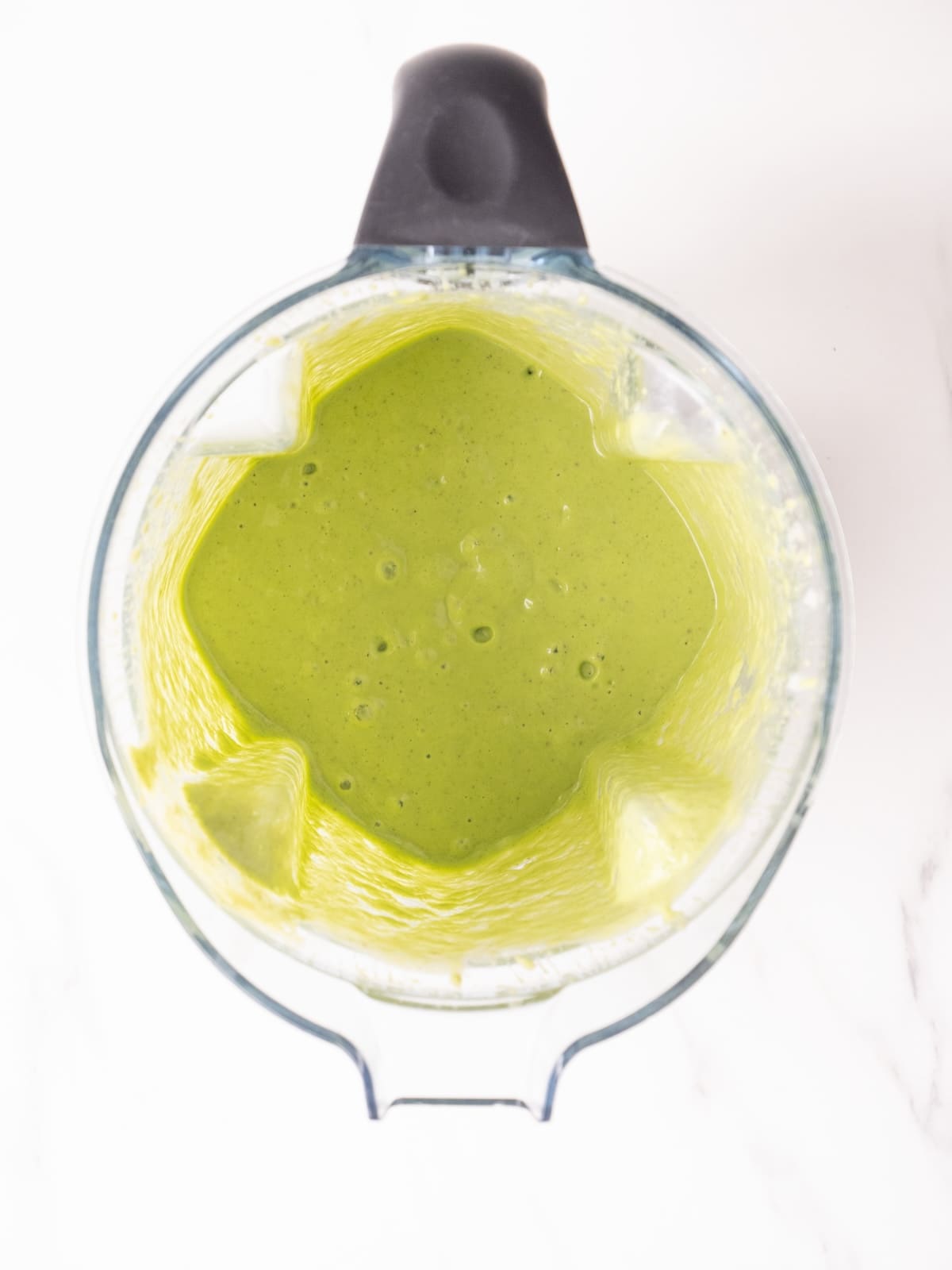An overhead shot of a blender with freshly blended breakfast spinach smoothie.
