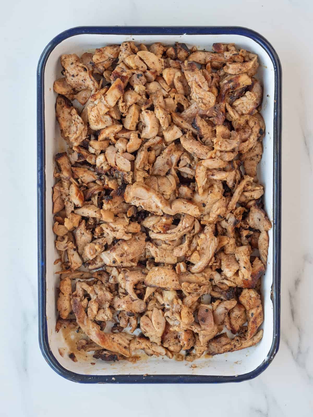 A rectangular dish with grilled chicken thighs sliced against the grain into thin strips.